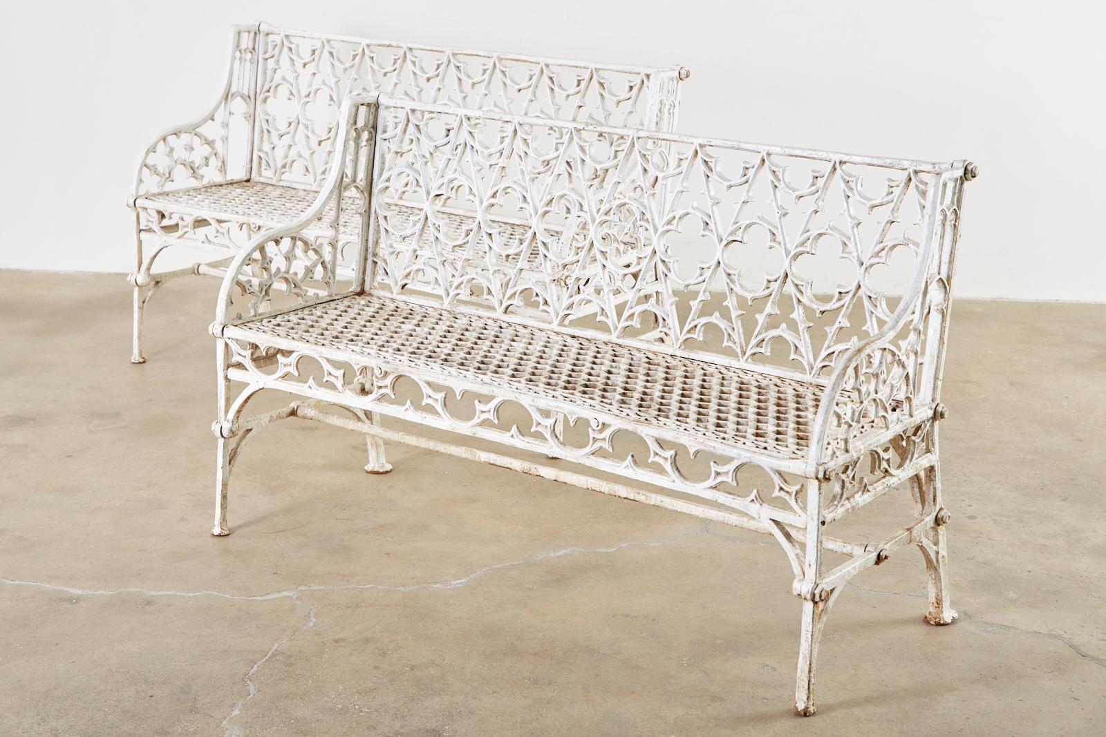 English Coalbrookdale foundry attributed cast iron garden benches. Made in the gothic revival English taste featuring gothic tracery backrest centered by quatrefoil designs. The gracefully curved arms enclosing demilune motif patterns. The seat has