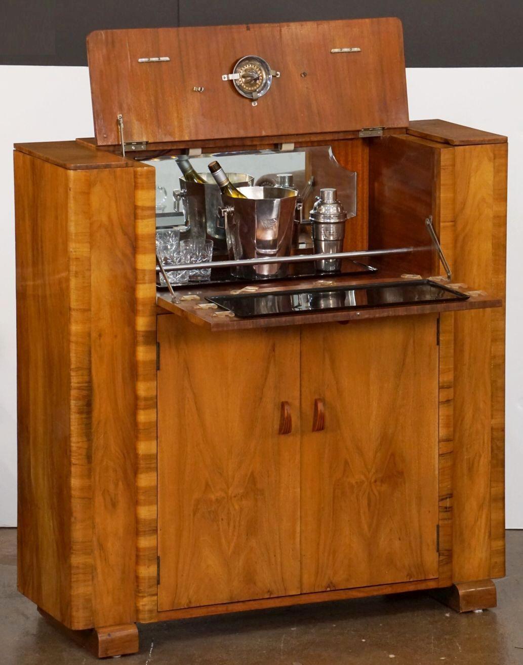 A fine English upright cocktail bar cabinet or drinks cupboard of flame and toned walnut from the Art Deco Period.

Featuring a dry bar top - opening to reveal a lighted, bevel-mirrored glass interior, with drop-down shelf for preparing cocktails,