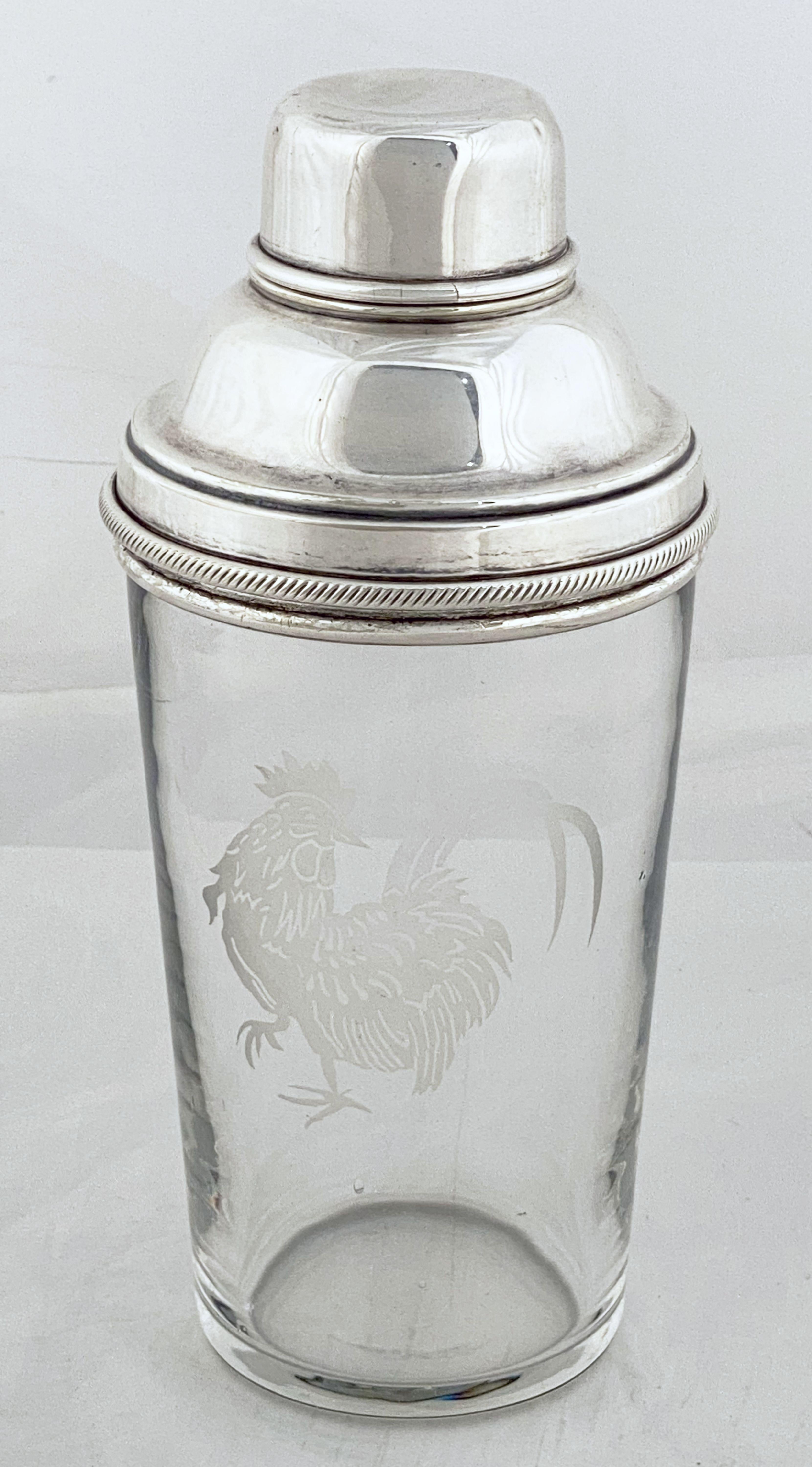 A large vintage English cocktail drinks or martini shaker of glass with removable cap and strainer of fine plate silver, 1 pint, featuring an etched cockerel on a cylindrical body.

Marked inside of cap: James Dixon and Sons hallmark, Made in
