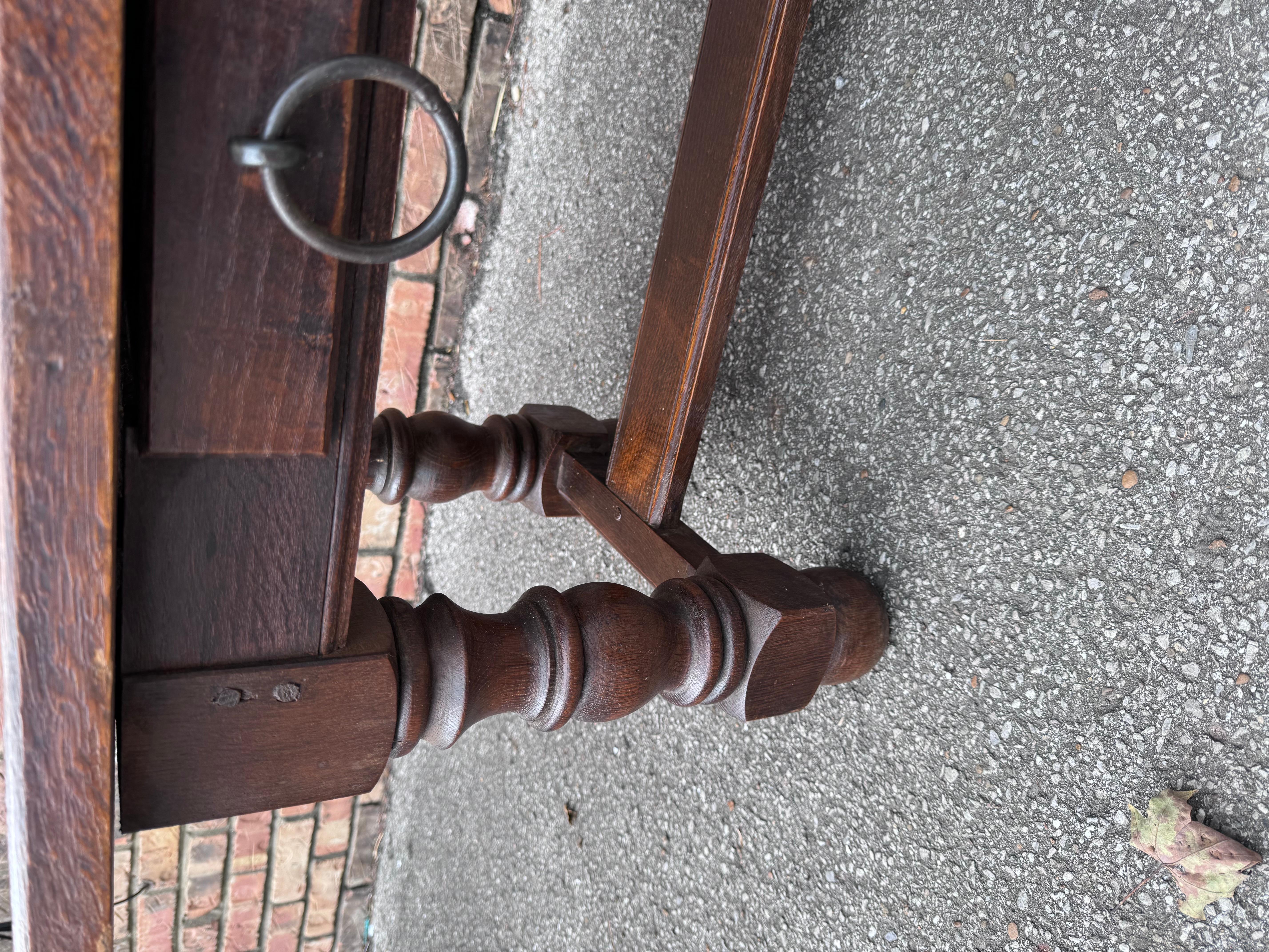 This is vintage English dark oak coffee table feature two drawers, both with round iron pulls. The top is thick and solid, resting on chunky turned legs even though this coffee table is not antique it's still wooden pegged together showing unique