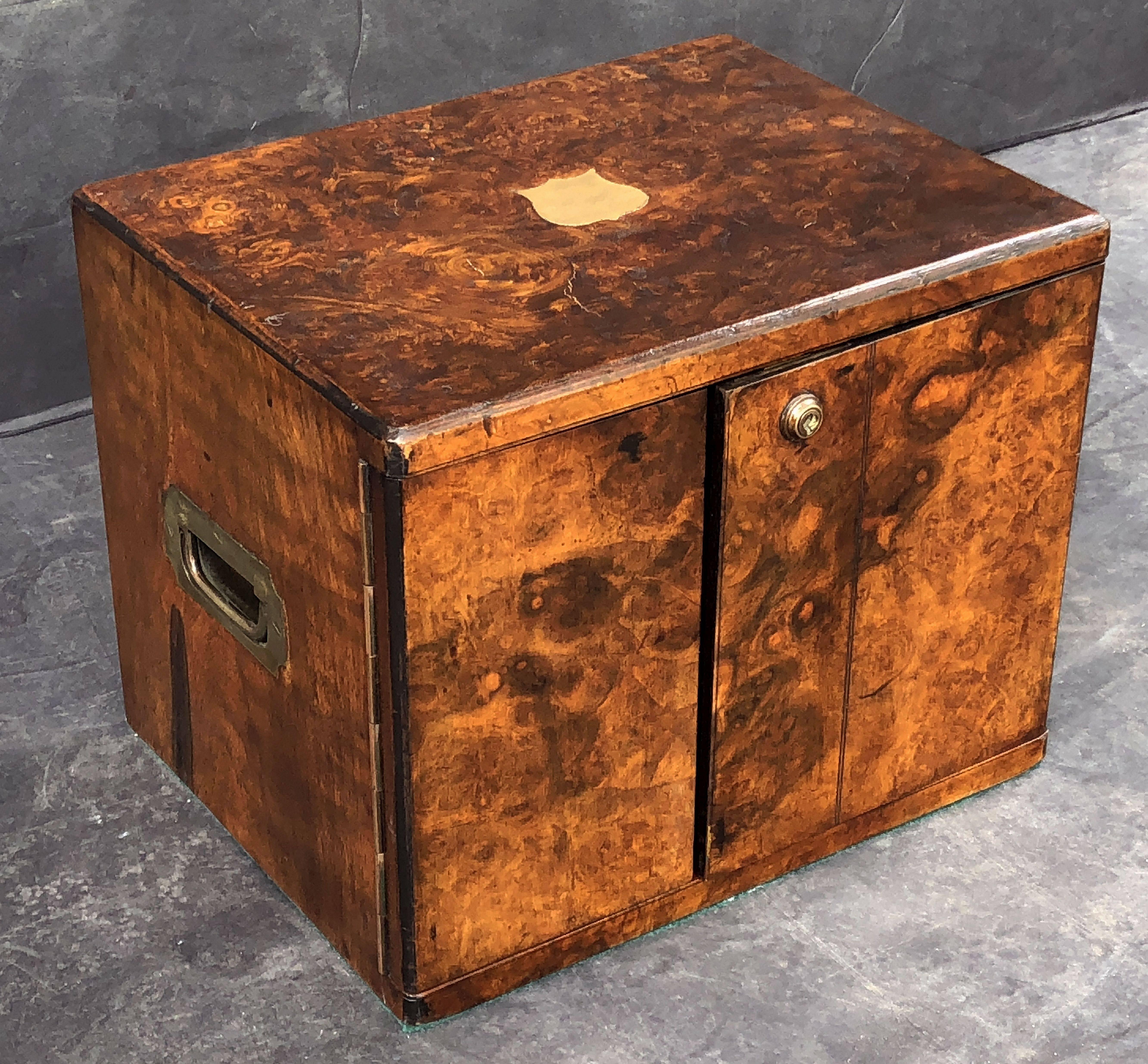 A fine English collector's cabinet box of brass-bound burr walnut, featuring a moulded top with brass chevron inlay to the center, over two small cabinet doors, opening to two drawers with recessed brass hardware. The exterior with figured wood all