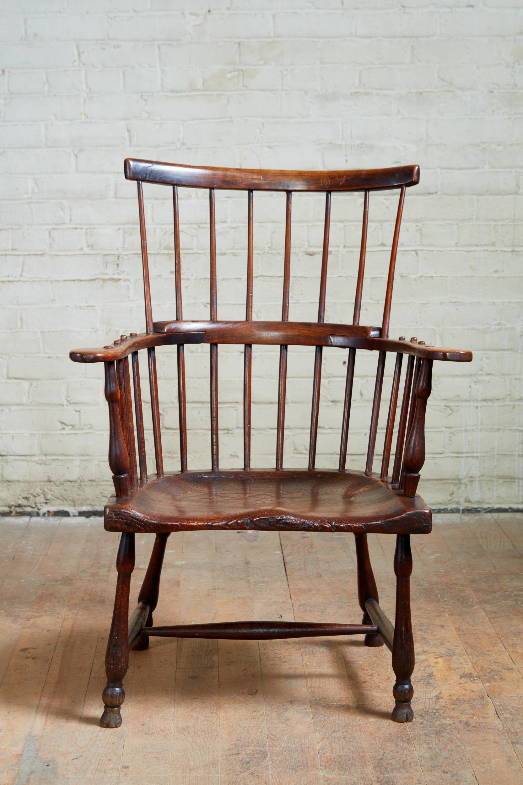 Fine 18th century English comb back Windsor armchair, the shaped crest supported by eight spindles, having scrolled arms with turned supports over deeply saddled 