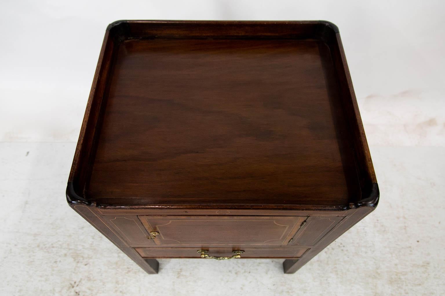 This commode is inlaid and crossbanded with boxwood, ebony, and satinwood. The handles are later. The lower pullout compartment has been converted to a drawer.