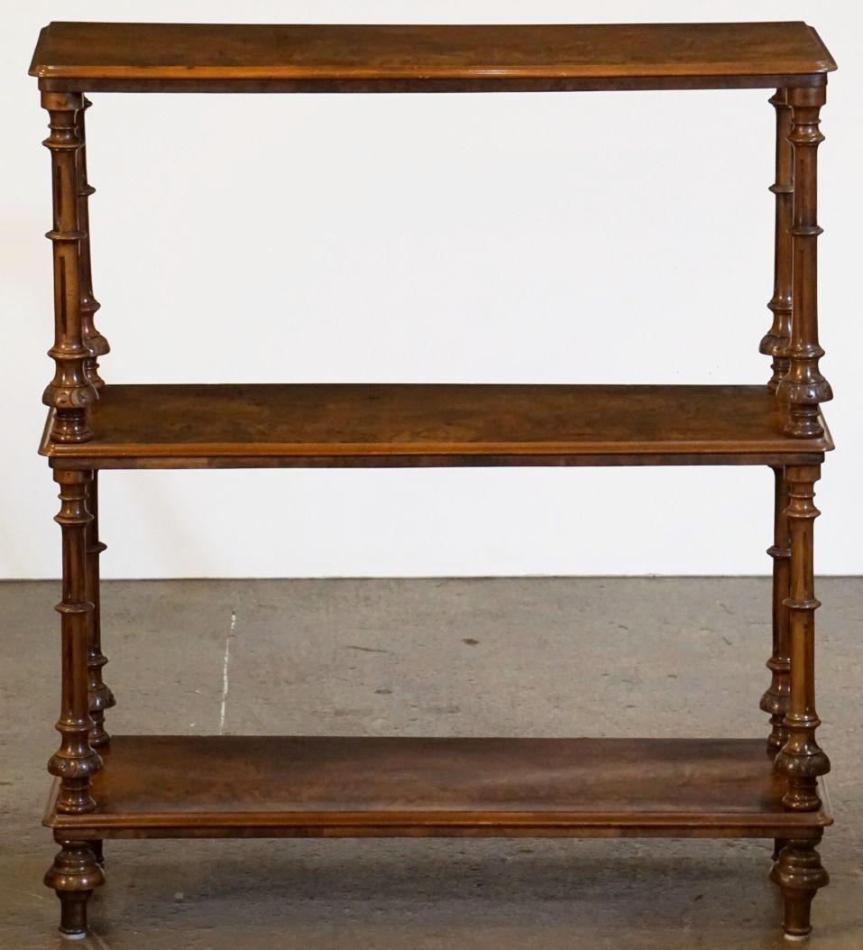 A fine English rectangular console buffet or shelving unit of burled or burr walnut from the late 19th century, featuring three tiers or moulded shelves and four turned supports, resting on raised feet.