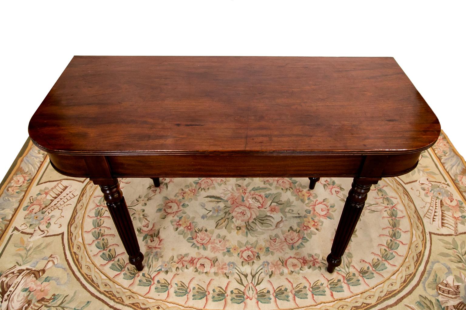 The top of this mahogany table has a reeded edge. The legs have heavy reeding.