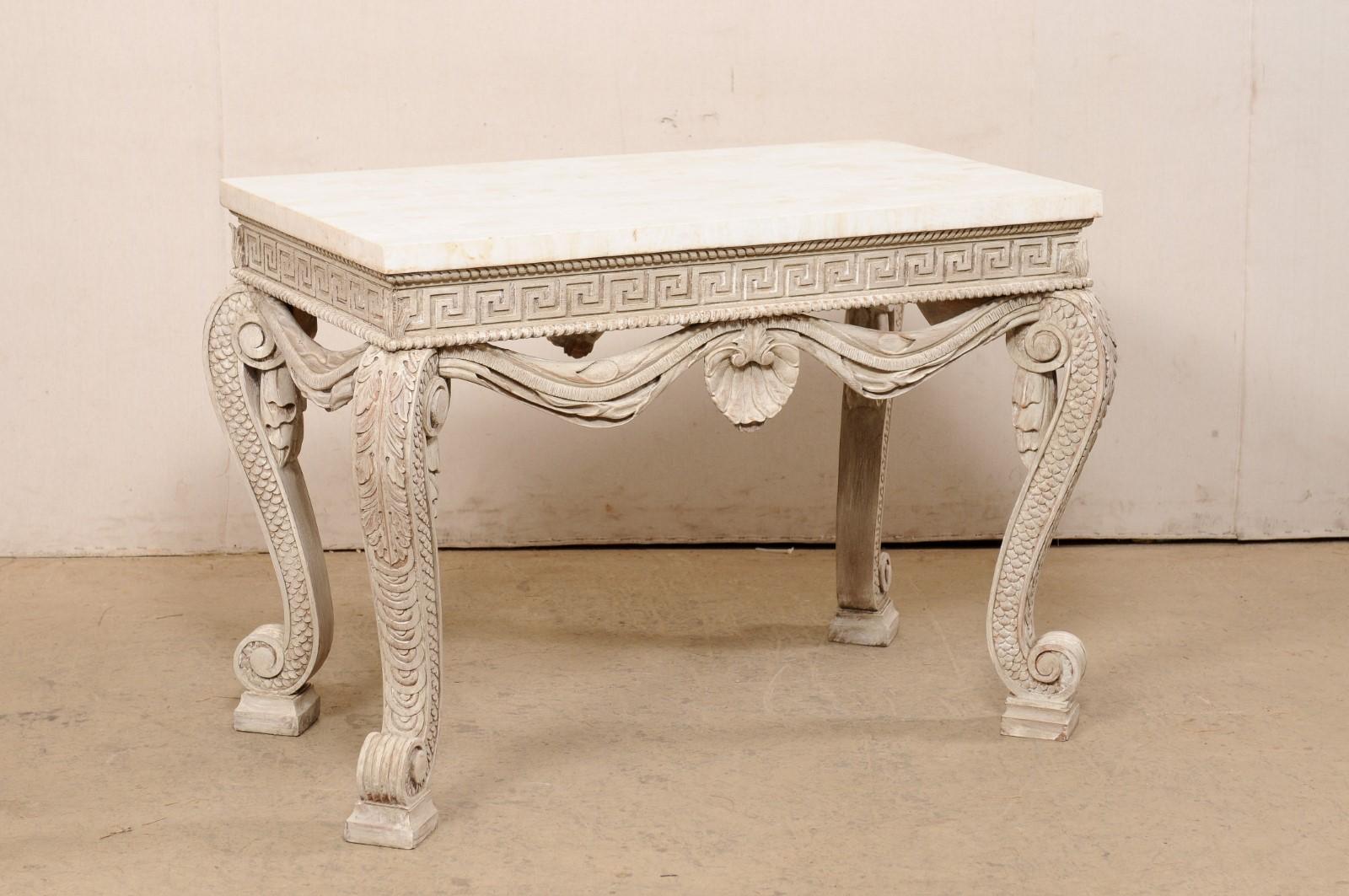 An English elaborately carved and painted wood table with tessellated travertine top, from the the mid 20th century. This vintage occasional table from England has a rectangular-shaped tessellated travertine top, above a wood apron carved with a