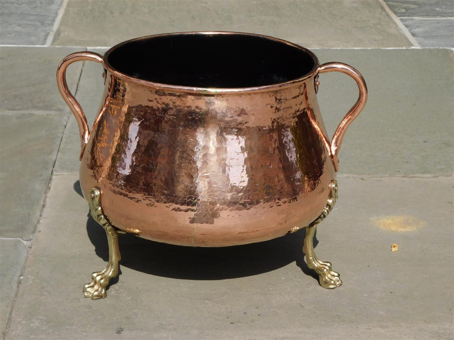 English copper hand hammered & cast brass jardiniere with a rolled rim, flanking scrolled side handles, and resting on the original acanthus lion paw feet, Early 19th Century.