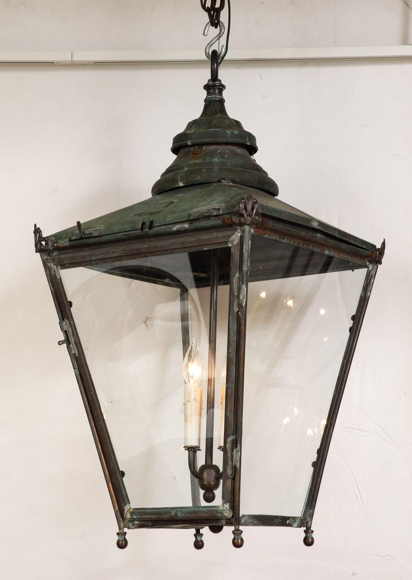 English 19th century copper and glass hanging hall lantern with hip roofed copper top surmounted by double vented rose with integral hanging ring, featuring decorative corner mounts, four canted sides with glass lites of which one is an openable