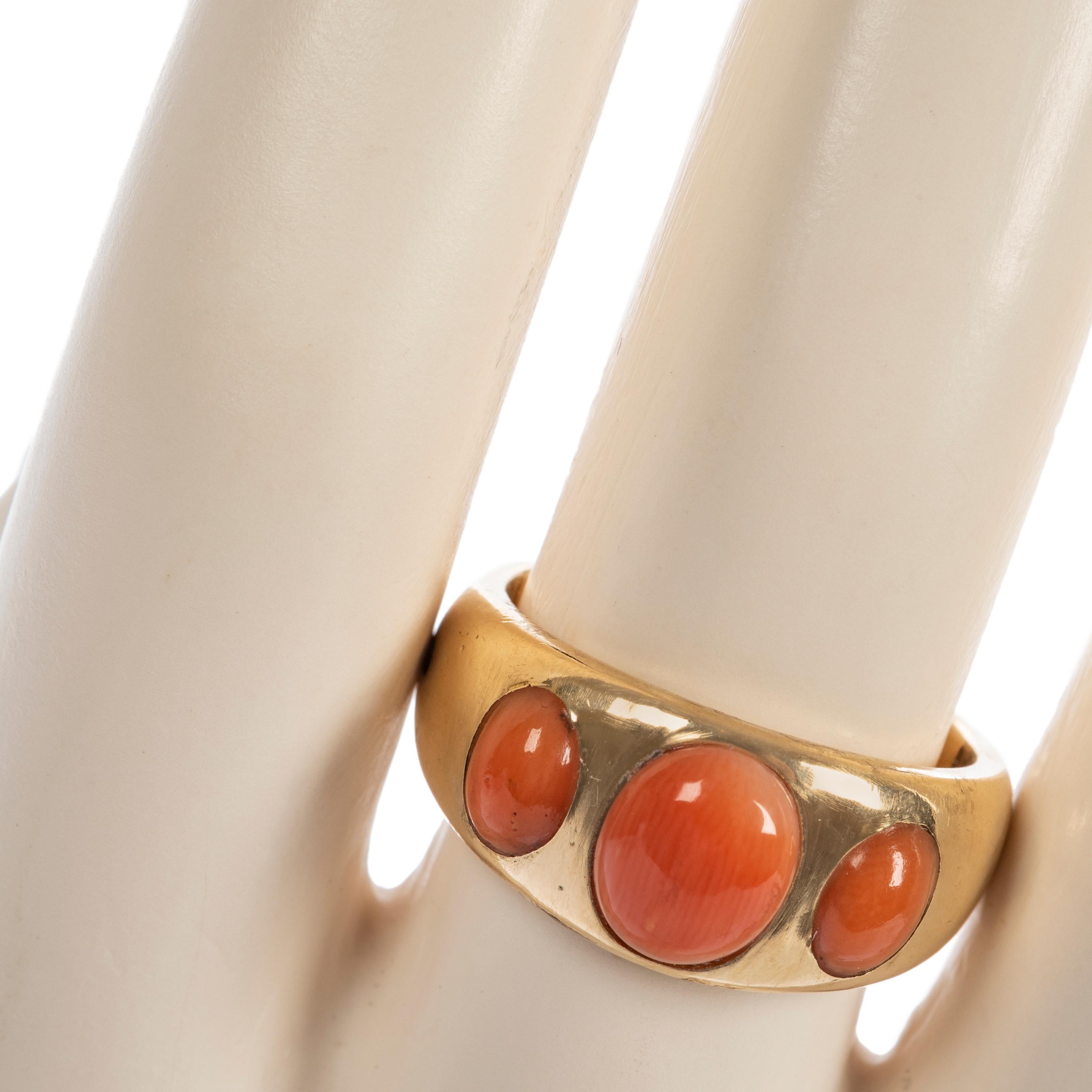 In polished 18k yellow gold of good weight, gypsy set with three coral cabochons.

Size-6 ¾; band measures 3/8 in. (1 cm) at its widest.

Fully hallmarked inside of shank with additional date letter mark on exterior, London, England, stamped JW
