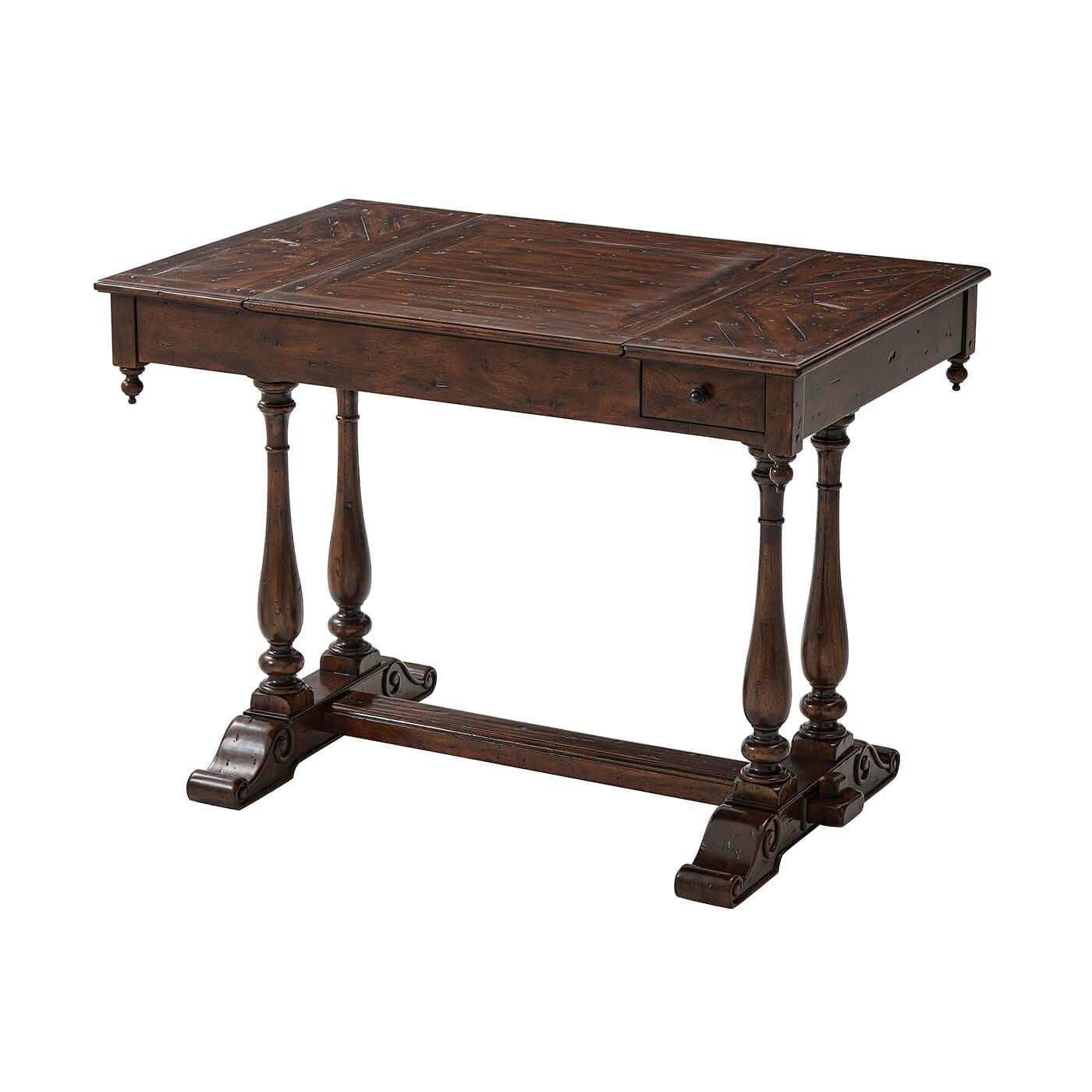 An antiqued wood games table, the rectangular top with a slide-out chessboard section revealing a backgammon board below, with two frieze drawers and turned finials, on twin turned baluster end supports, the base joined by a pegged stretcher. The