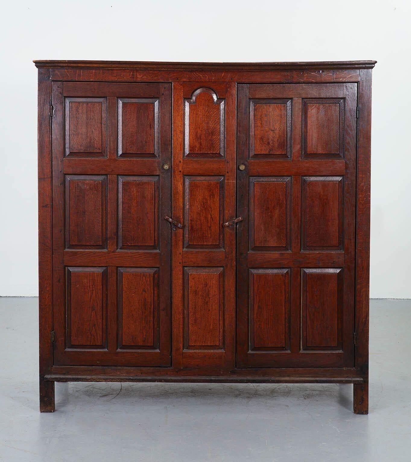 An 19th century English country house cupboard in oak with wonderful patination and superb color. Two doors within molded paneled front and sides and shaped and molded central arched panel below corniced top, all standing on stile feet, and with a