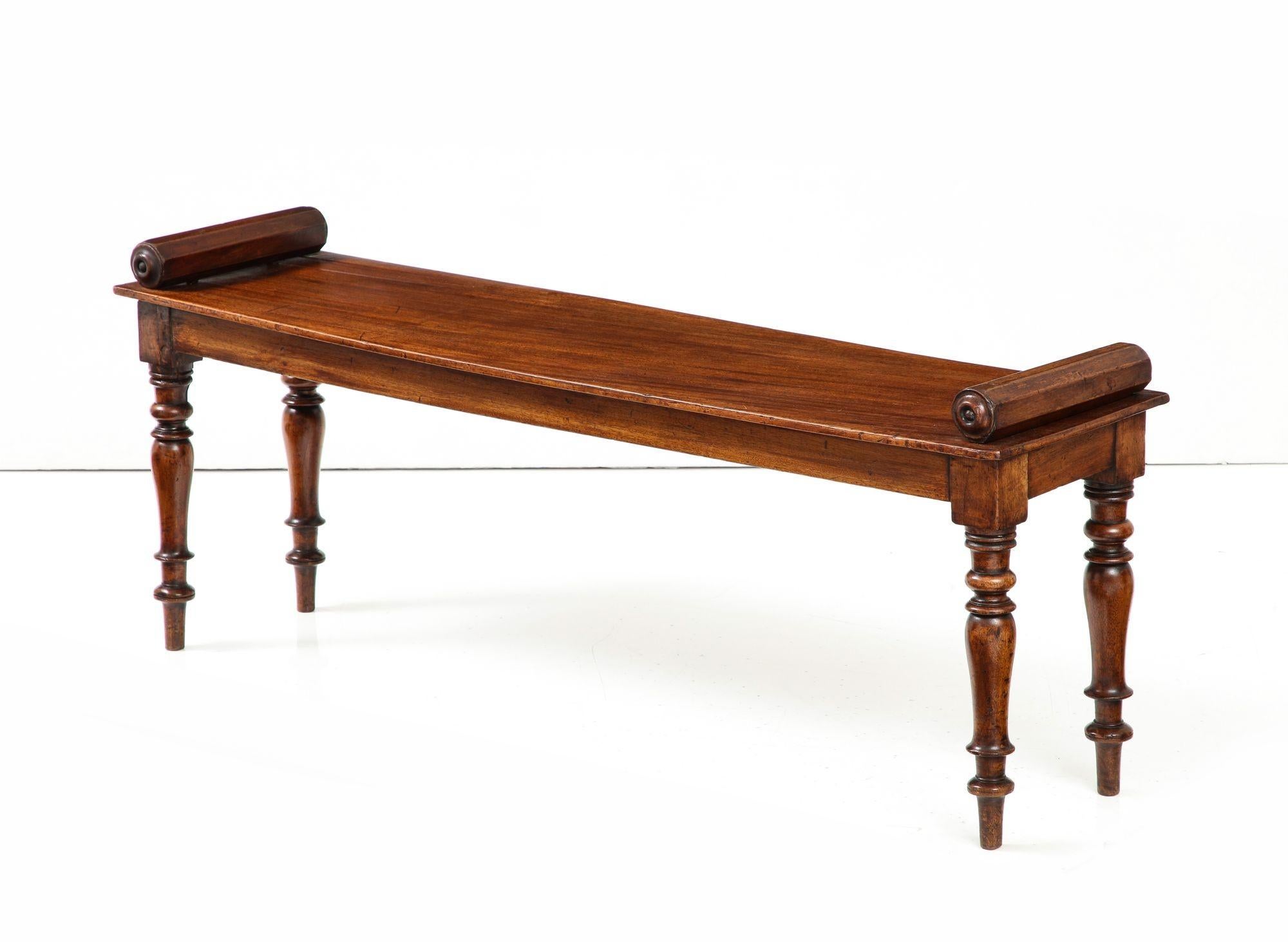 An early 19th century English mahogany hall bench having molded edge top with octagonal bolster ends on shallow apron with baluster turned legs. Can be used with or without loose custom-made Fortuny cushion seen in photos.