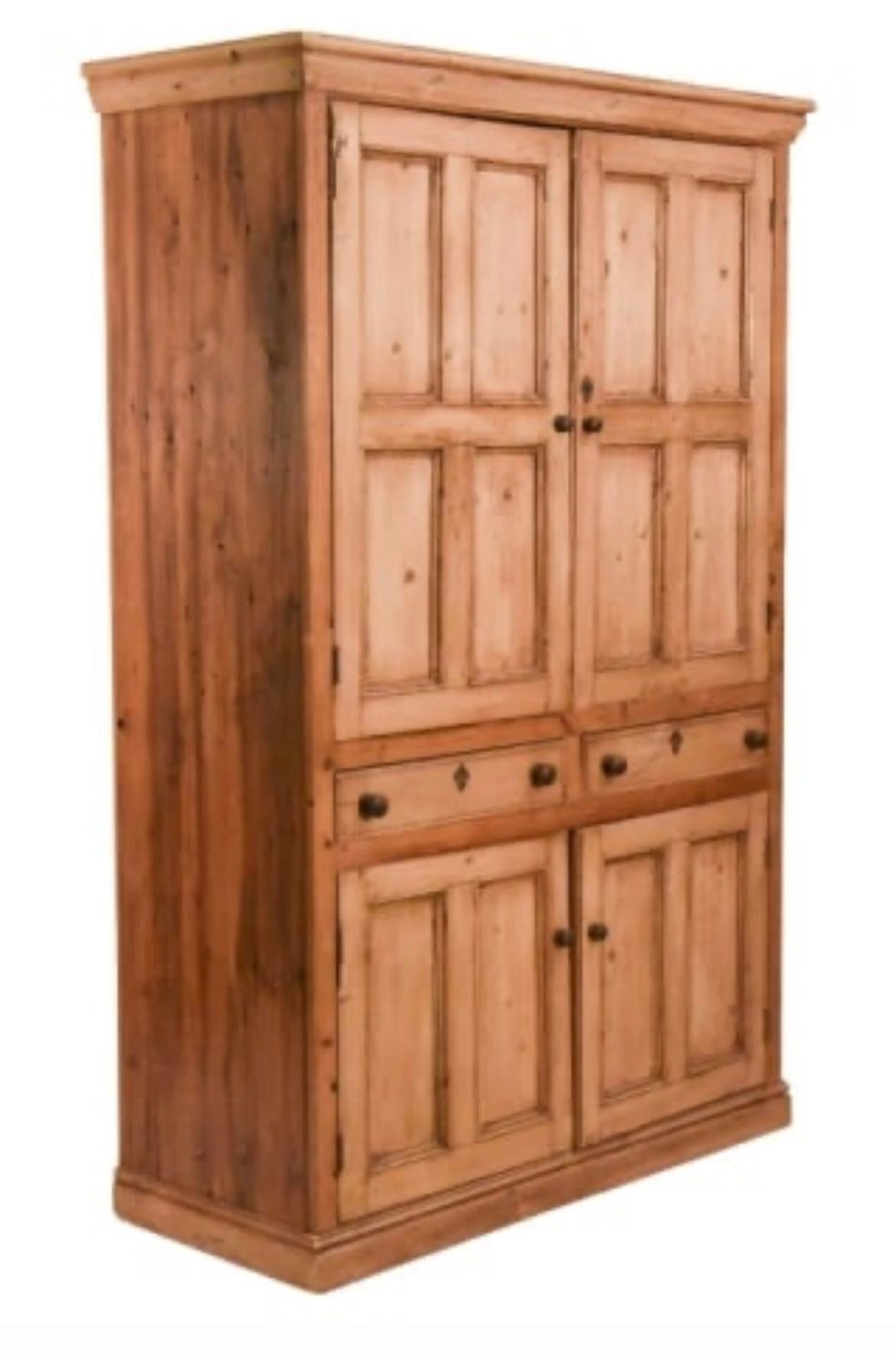Mueble para ropa blanca de estilo rústico inglés, de pino, con 2 puertas paneladas que ocultan un estante interior, sobre un par de cajones con pomos de madera, sobre un par inferior de puertas paneladas con estante interior. Cerradura y llave de