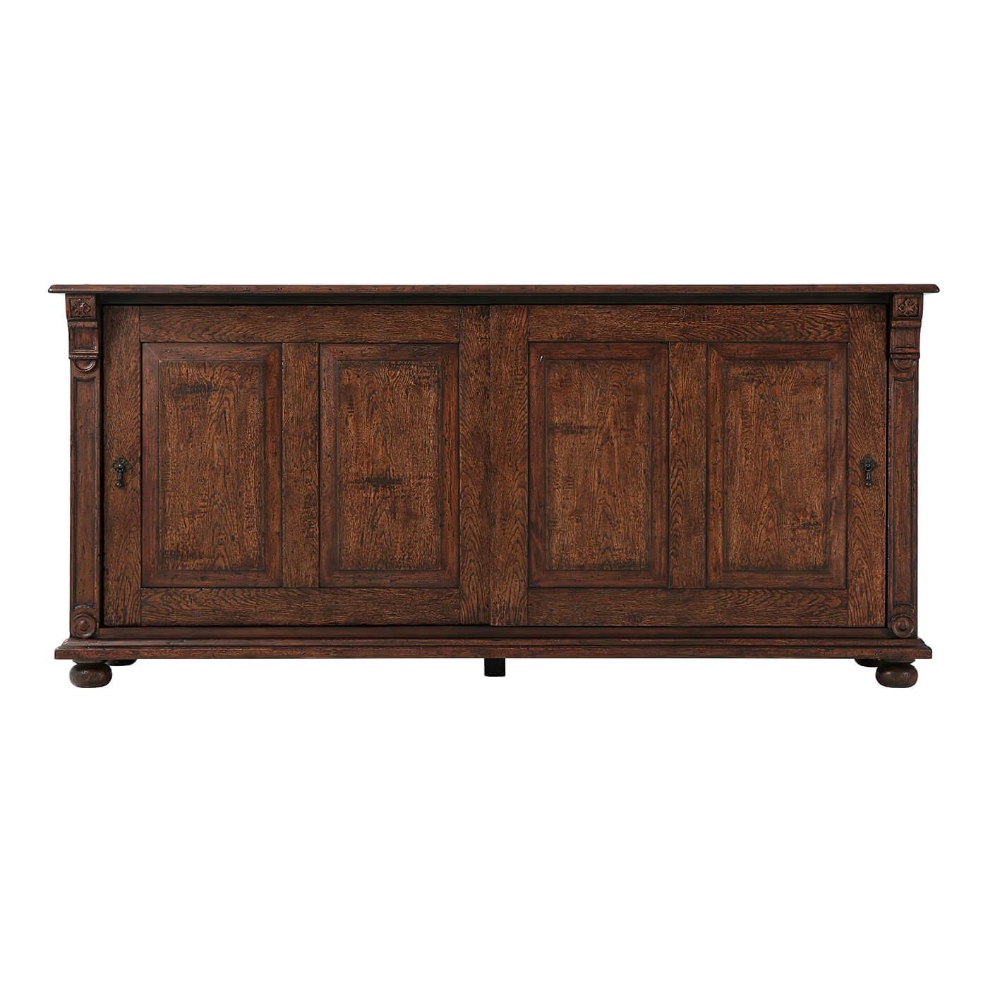 English Country Oak veneered sideboard with sliding doors. The rectangular top features a gentle moulded edge resting over two corbel columns and two chamfered sliding doors enclosing two drawers and an adjustable shelf. All of this rests upon a