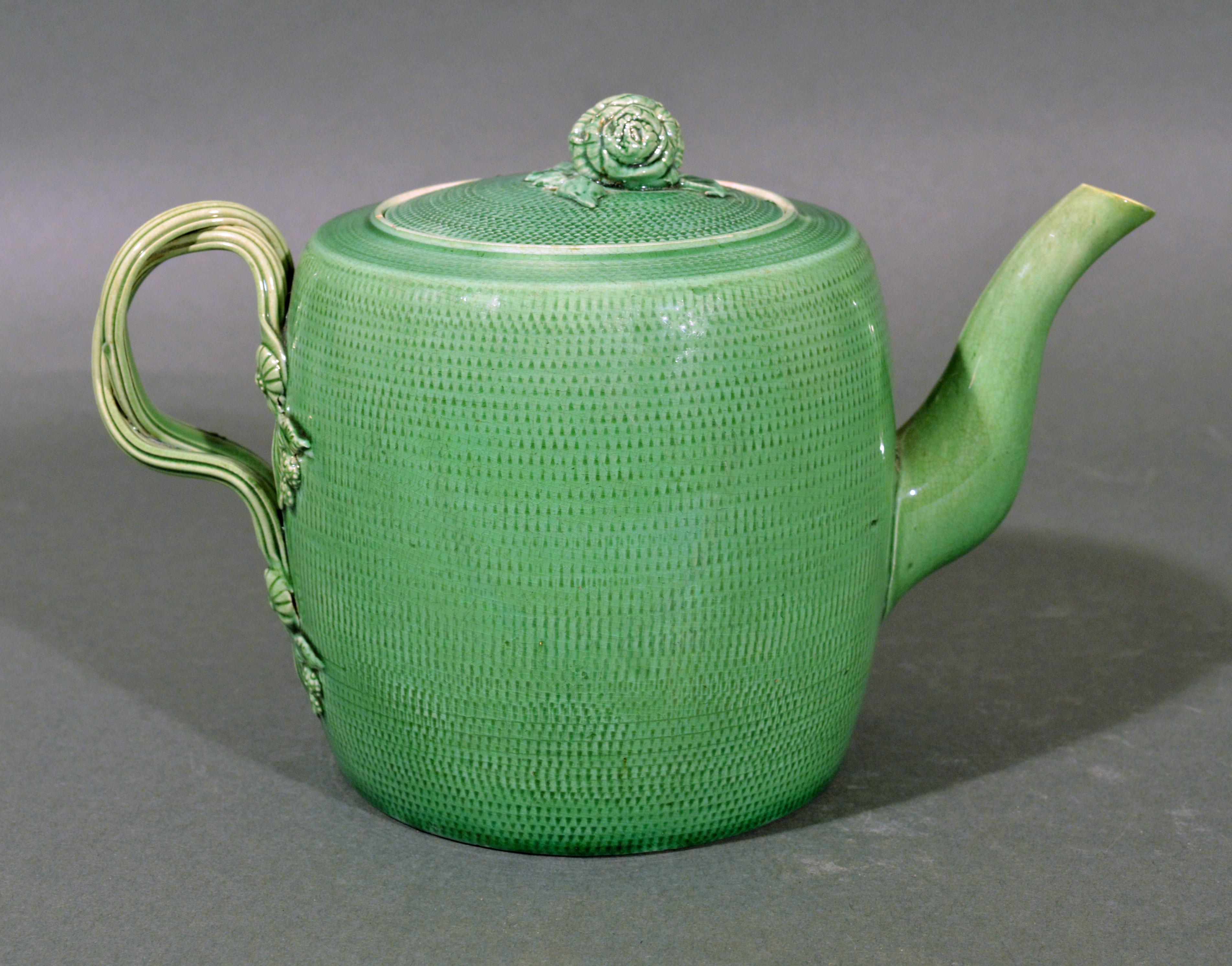 English creamware pottery green glazed teapot and cover, 
Swinton, Yorkshire, 
circa 1770 


The barrel-form creamware teapot is decorated with a dipped green glaze over an impressed overall rouletted design. The spout is plain and the handles