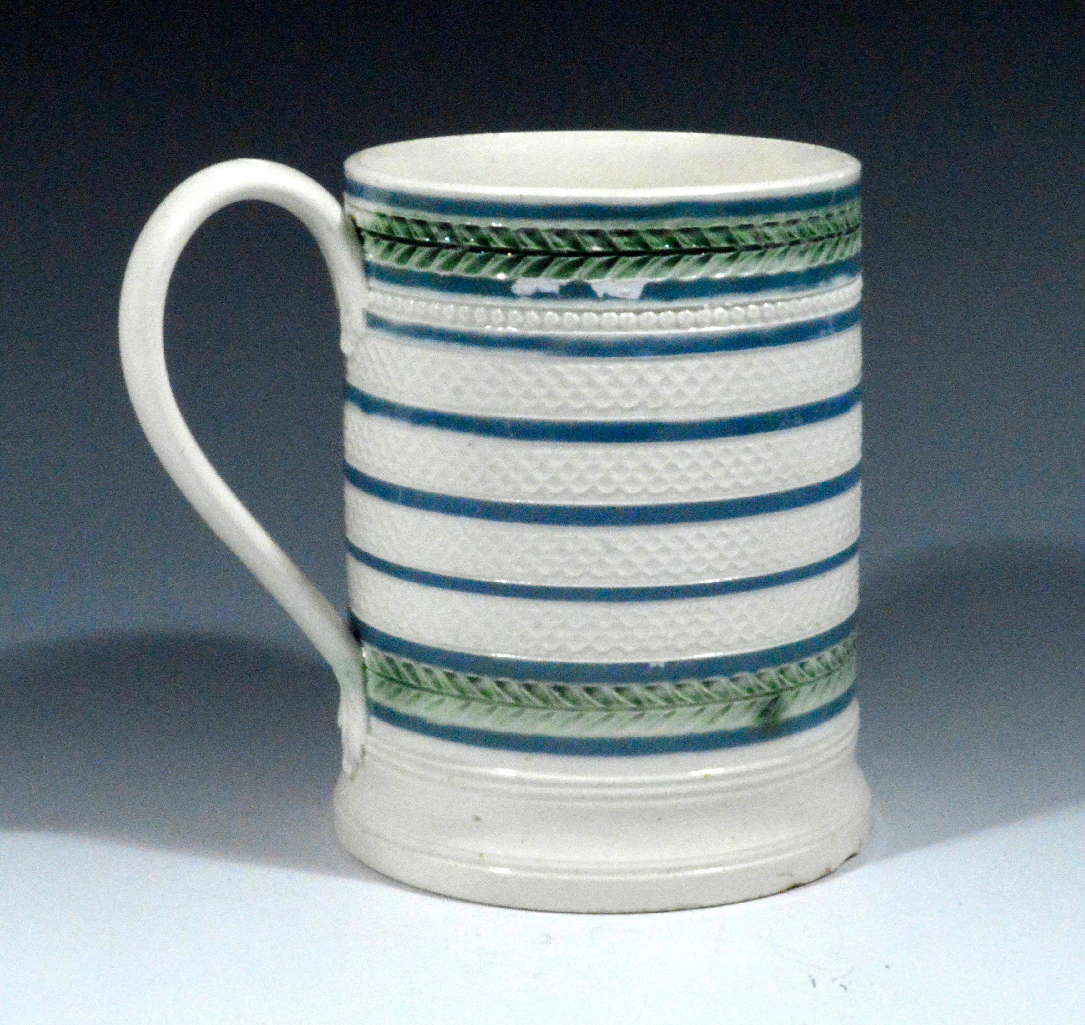 English creamware tankard, 
circa 1810-1820.

The creamware tankard is decorated with a series of moulded engine-turned honeycomb designs separated with bands of blue dip and above and below are green colored bands of continuous leaf