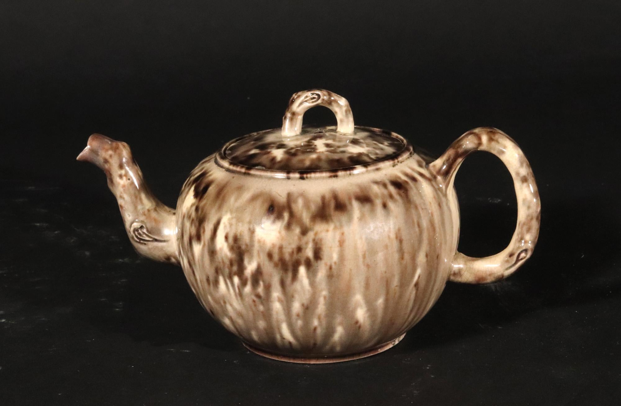 English Creamware Gray Tortoiseshell Lead Glaze Pottery Teapot and Cover,
Whieldon Type,
Circa 1765.

The creamware teapot and cover, of small circular form, are decorated with a lead glaze tortoiseshell glaze unusually colored gray. The cover with