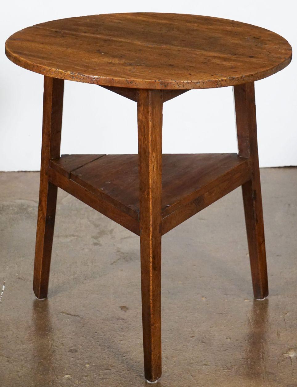 A handsome English cricket table of patinated wood from the Georgian Era, featuring the traditional round or circular top over a tripod base with pegged joins and triangular under-tier shelf.

Makes a nice occasional table or side table.

Dimensions