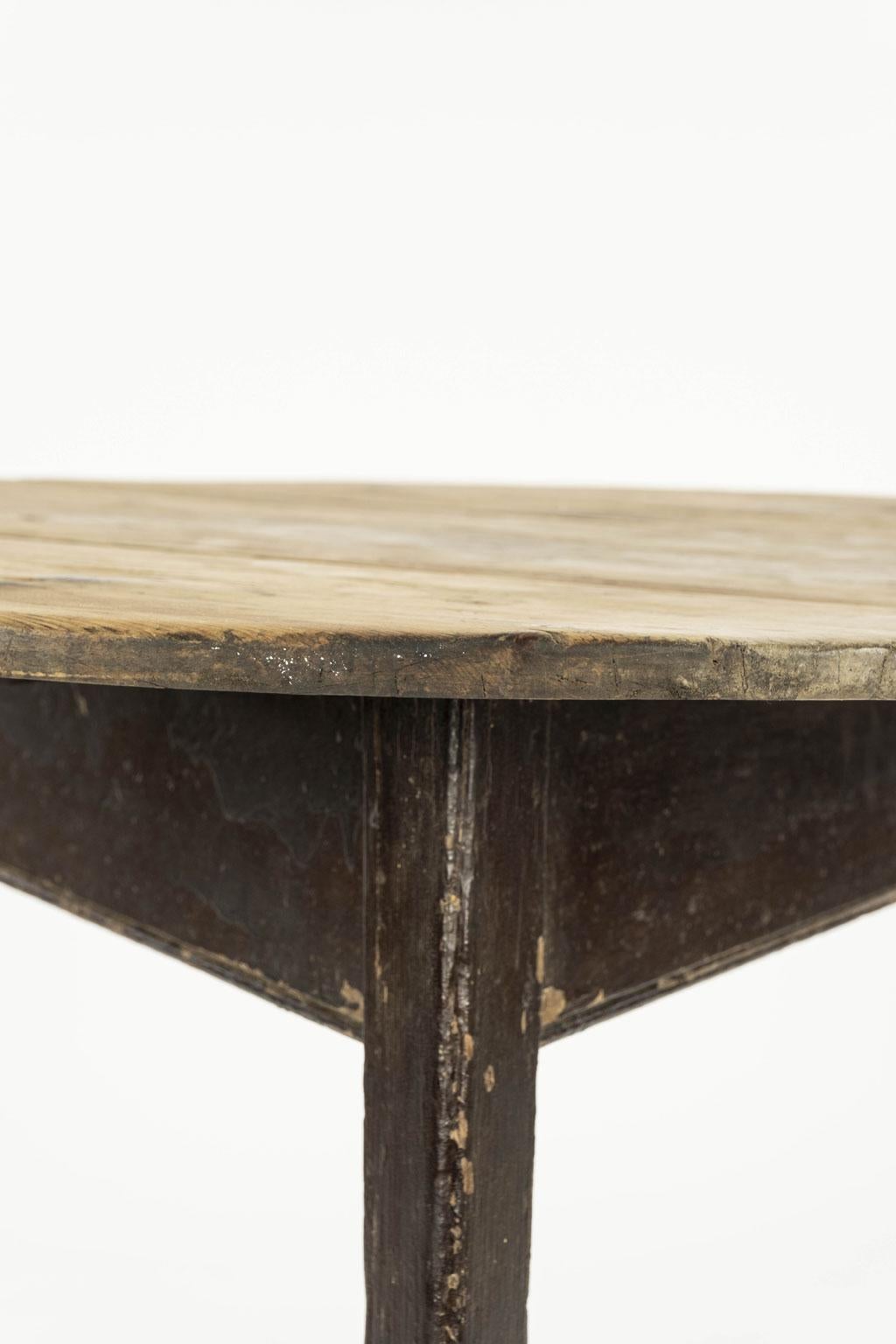 English cricket table in pine, dating to mid-19th century. Scrubbed round top supported by brown painted three-legged base. Brown painted finish is early. Some losses to finish.