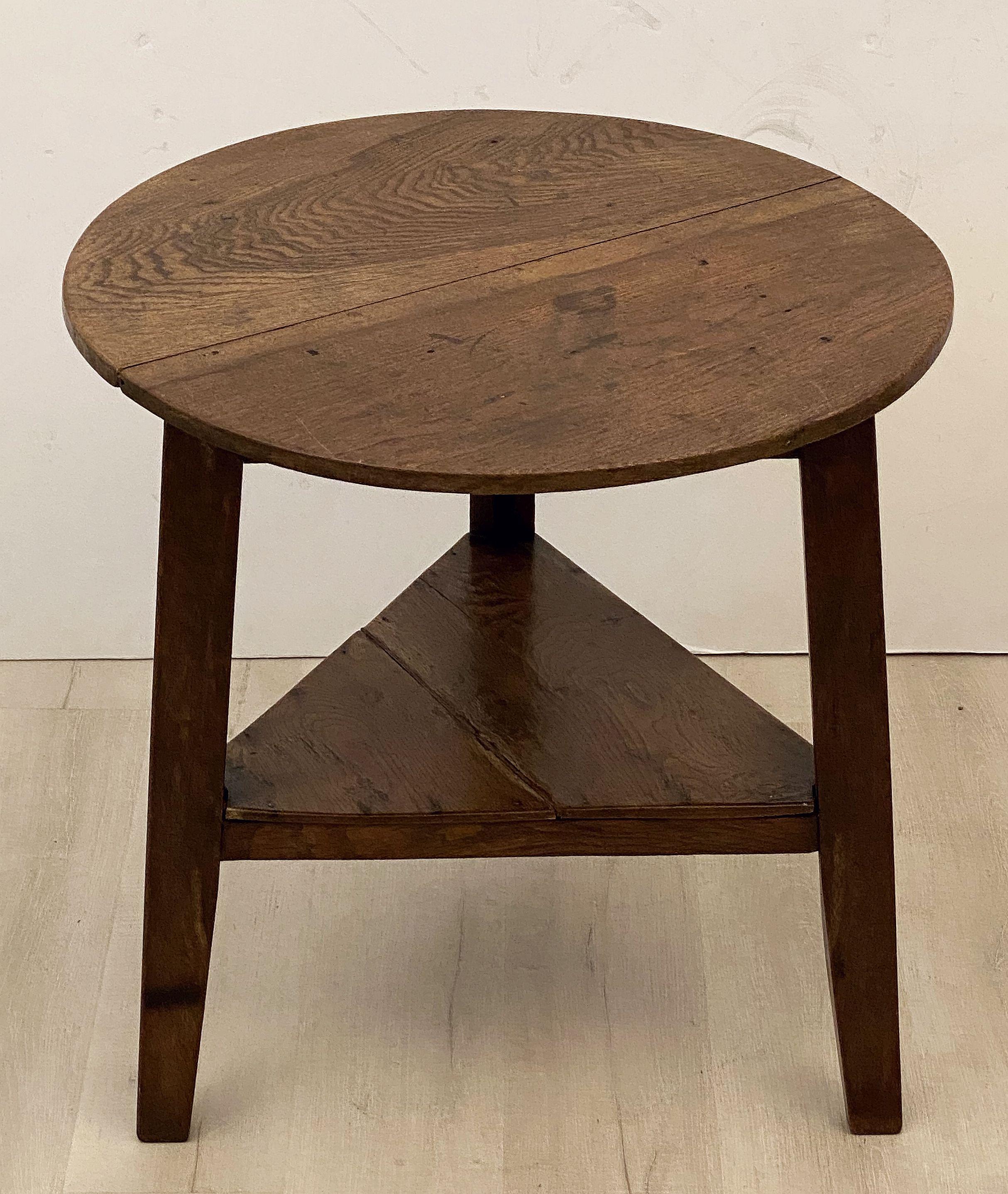 A fine English cricket table of oak featuring the traditional round or circular top over a tripod base with triangular under-tier shelf.

Makes a nice occasional table or side table.

Dimensions are height 28 inches x diameter 27 3/4 inches.