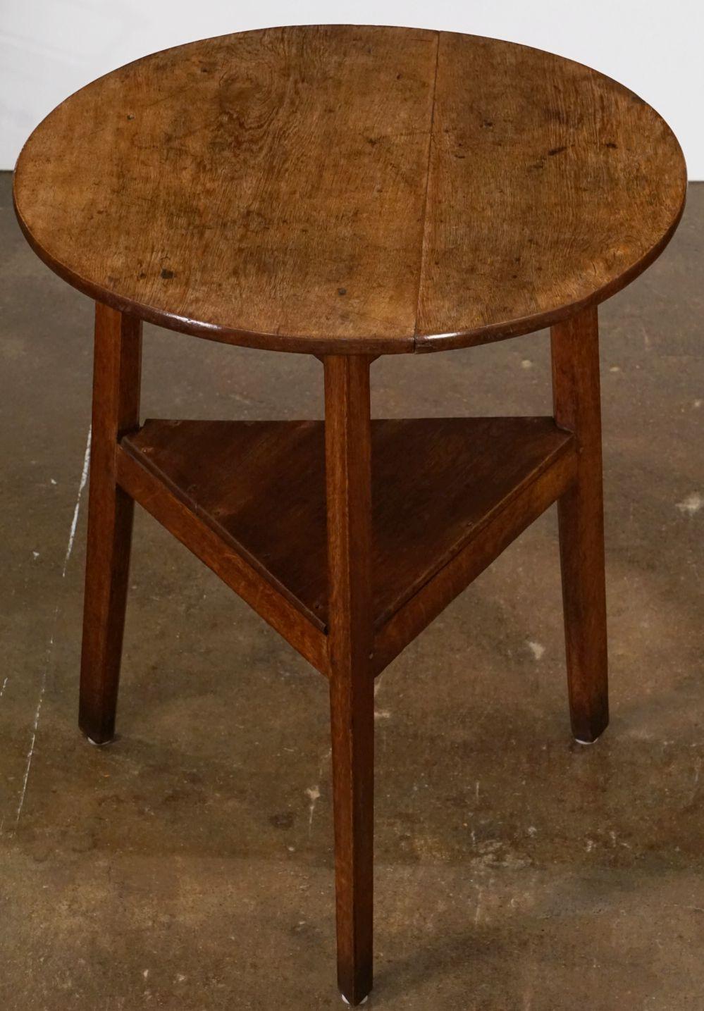 A fine English cricket table of oak featuring the traditional round or circular top over a tripod base with triangular under-tier shelf.

Makes a nice occasional table or side table.

Dimensions are height 32 inches x diameter 28 1/8 inches.