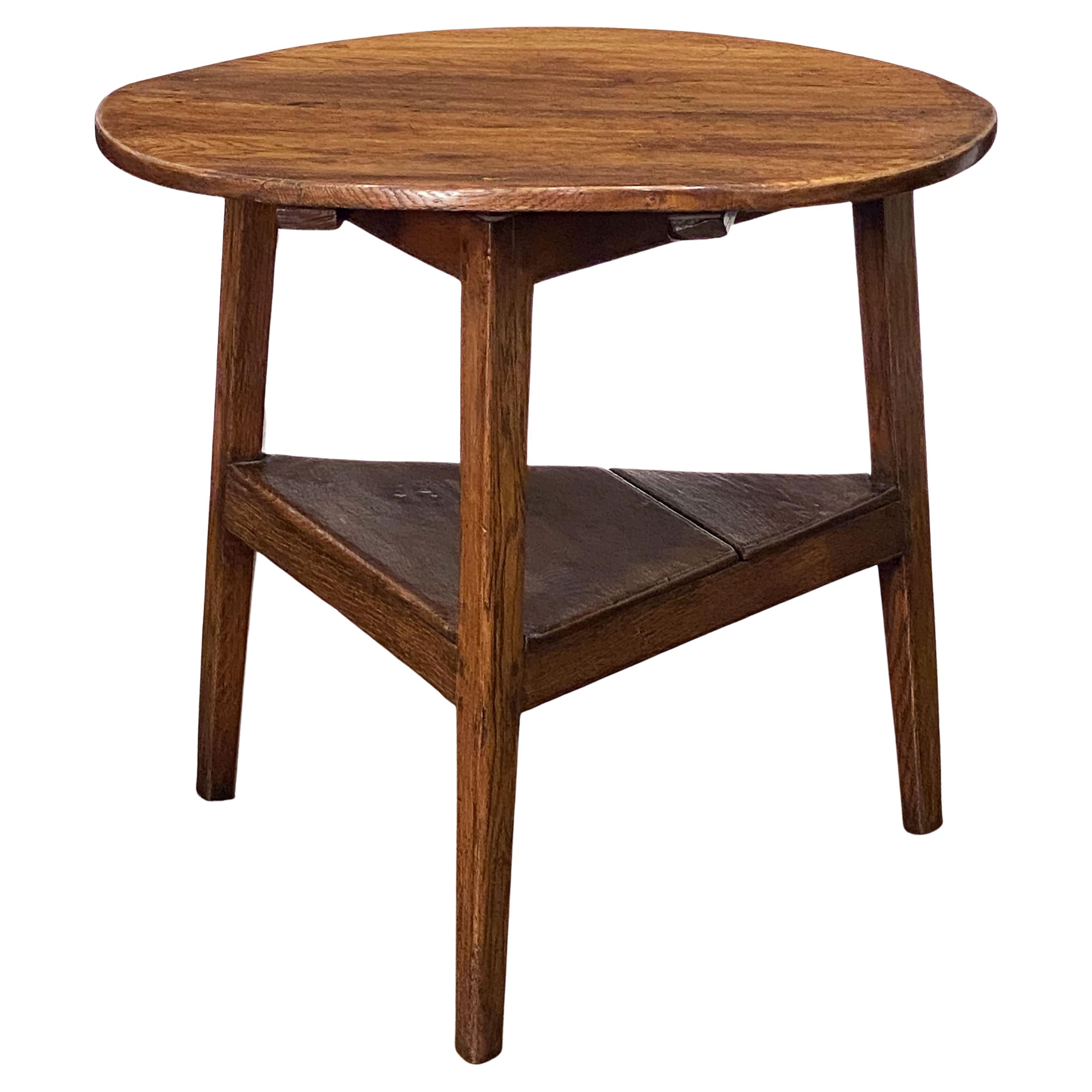 A fine English cricket table of patinated oak from the late Georgian era, featuring the traditional, rustic round or circular dowel-pegged top over a tripod base with triangular under-tier shelf.

Makes a nice occasional table or side