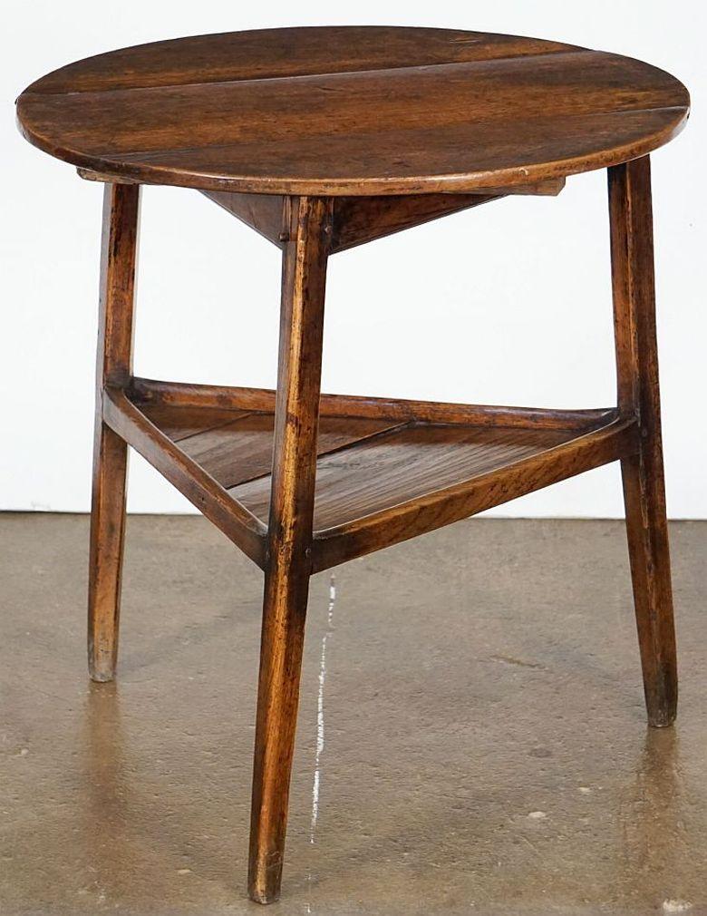 A fine English cricket table of patinated oak from the George III period, featuring the traditional round or circular top over a tripod base with pegged joins and triangular under-tier shelf.

Makes a nice occasional table or side table.

Dimensions