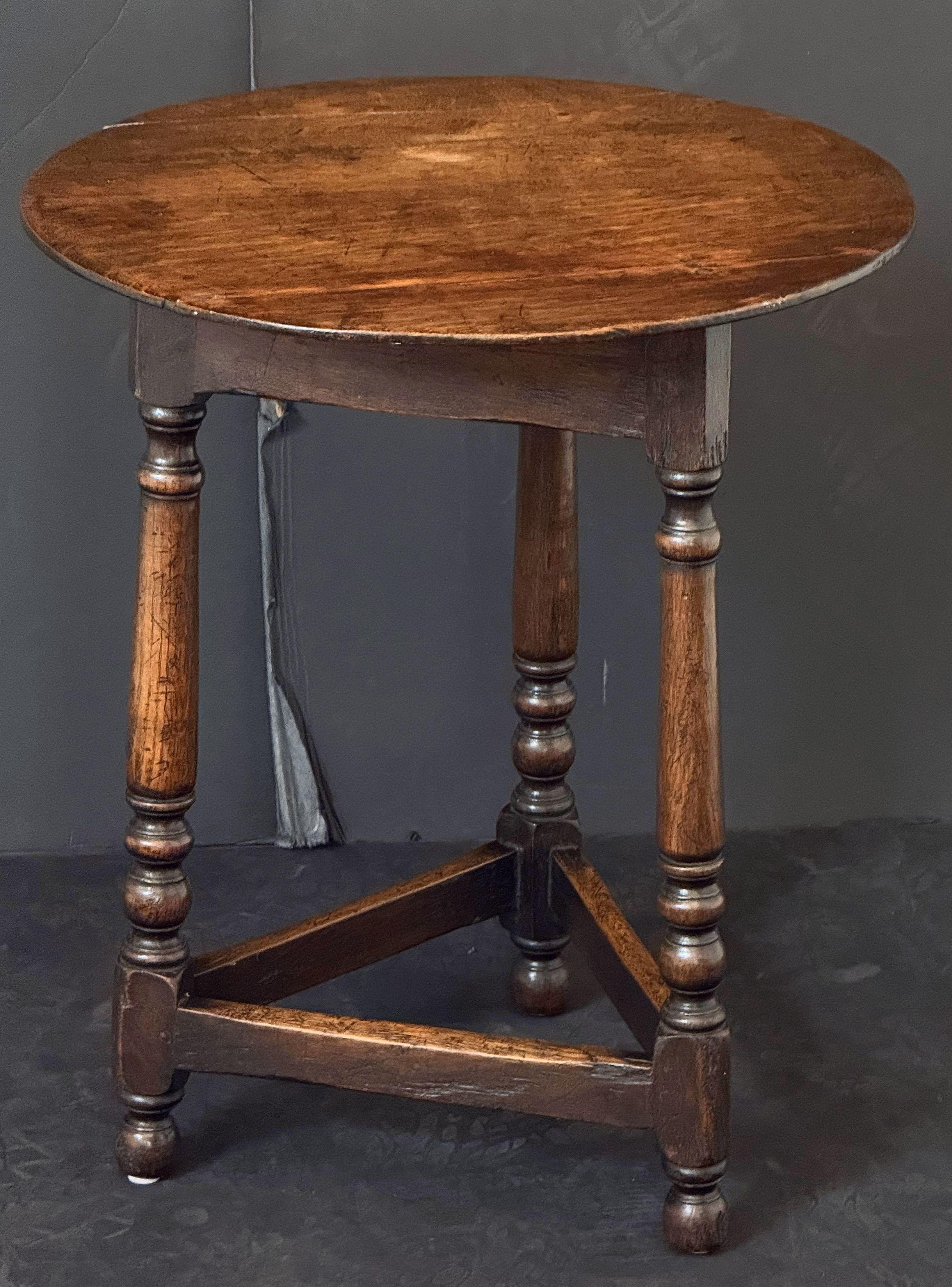 A handsome English cricket table of patinated wood from the Georgian Era, featuring the traditional round or circular top over a tripod base with turned leg supports, pegged joins, and triangular brace.

Makes a nice occasional table or side