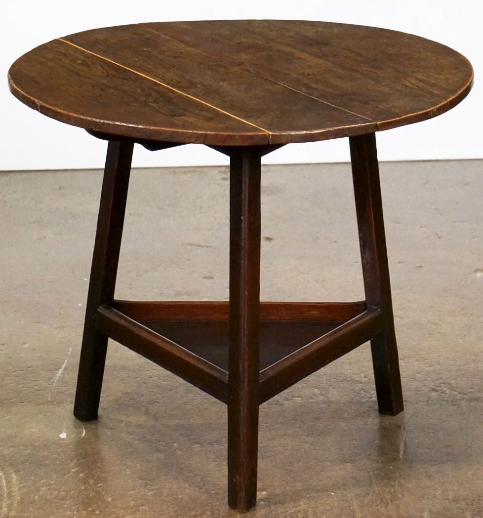 A fine English cricket table of oak featuring a traditional round or circular top over a tripod base with triangular under-tier shelf but with the added feature of a fold-down leaf.

Makes a nice occasional table or side table.

Dimensions are