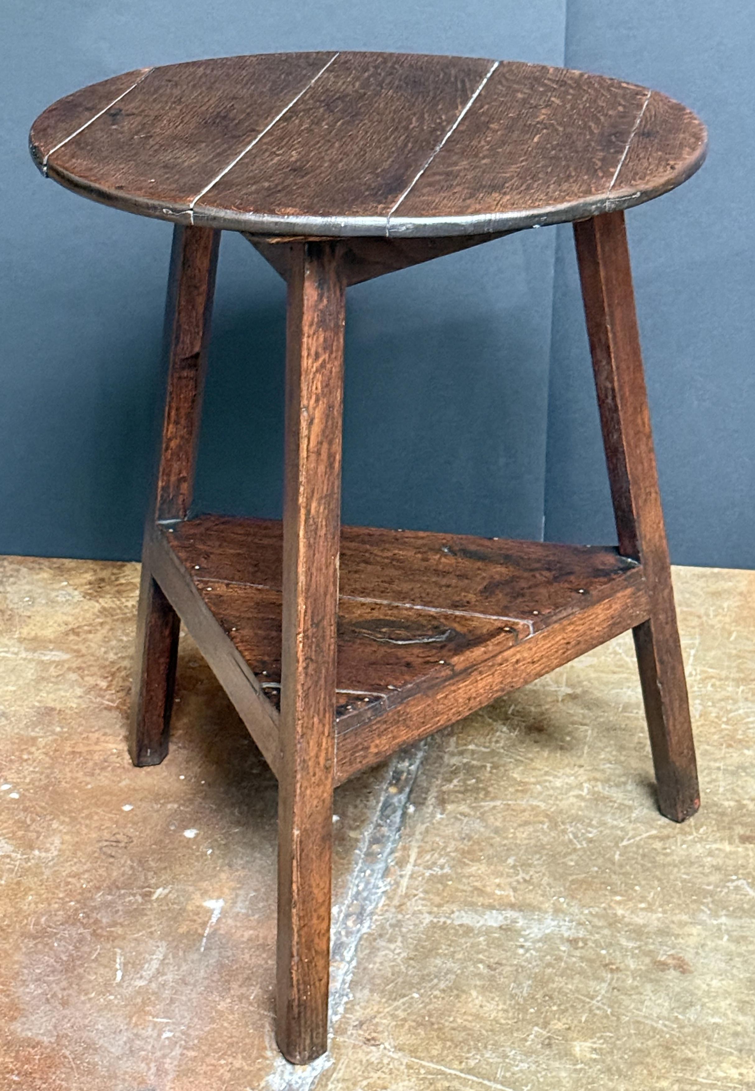 A handsome English cricket table of patinated oak from the Georgian Era, featuring the traditional round or circular top over a tripod base with pegged joins and triangular under-tier shelf.

Makes a nice occasional table or side table.

Dimensions