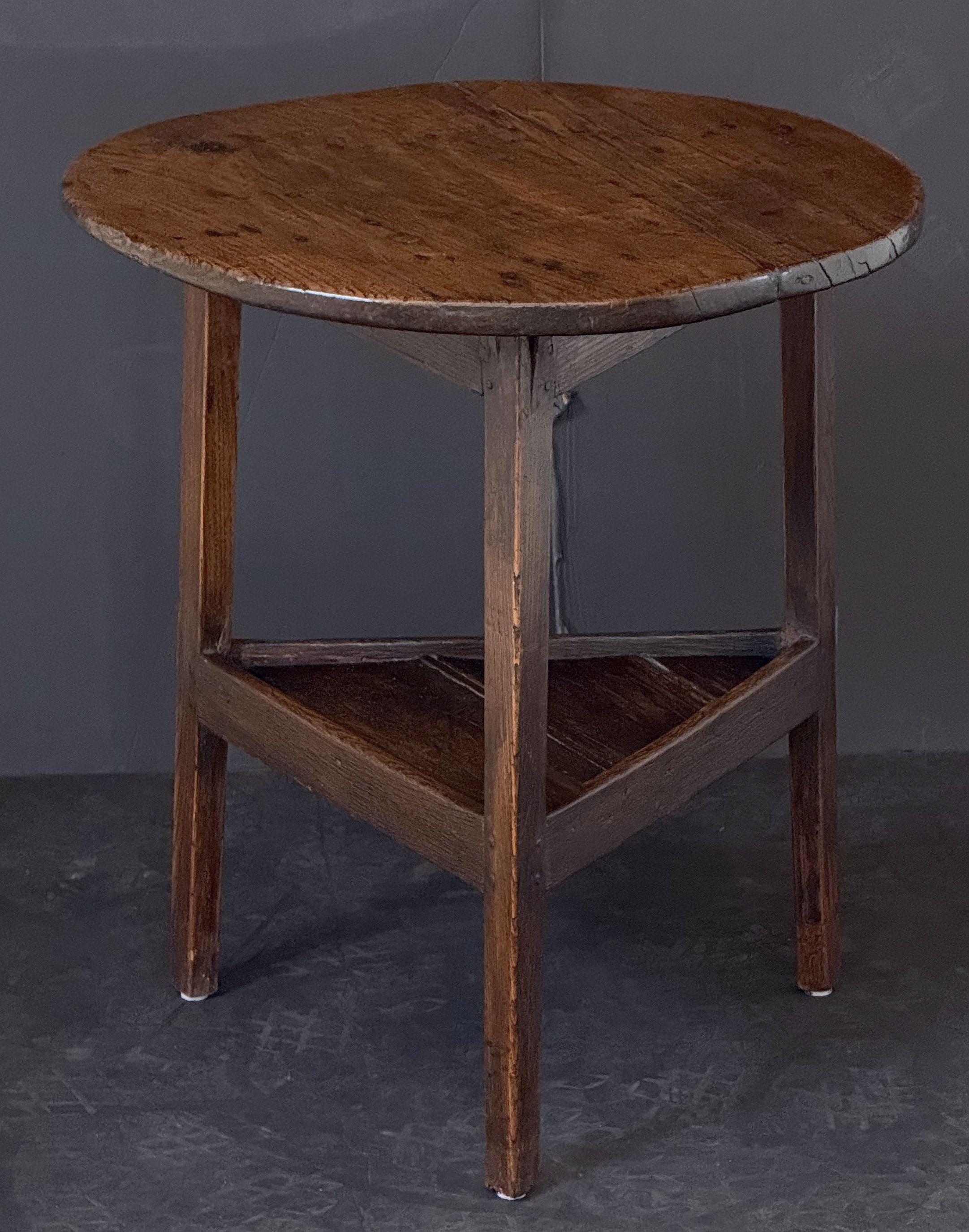 A handsome English cricket table of patinated oak from the Georgian Era, featuring the traditional round or circular top over a tripod base with pegged joins and triangular under-tier shelf.

Makes a nice occasional table or side table.

Dimensions