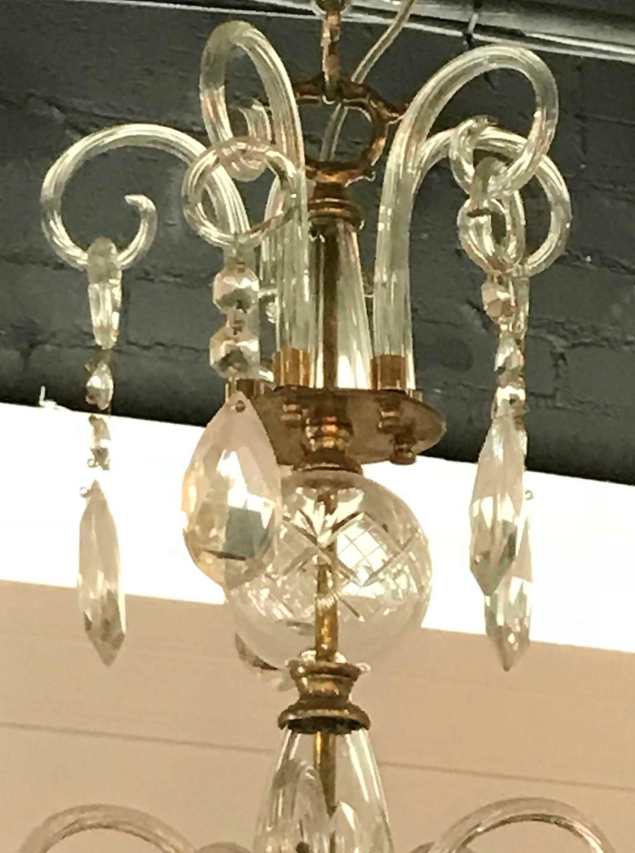 Lovely English brass, blown glass, and crystal chandelier. The crown with blown glass loops with suspended almond-shaped prisms atop a shaped stem surmounted with scrolled arms having cut crystal bobeche decorated with bead and pear-shaped prisms.