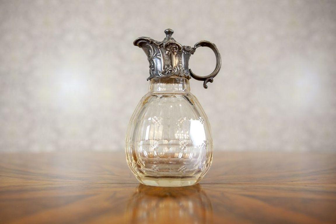 English Crystal Pitcher with Handle from the Turn of the Centuries

A small English pitcher with a lid and a silver-plated handle, made of crystal glass, dated to the turn of the 19th and 20th centuries.