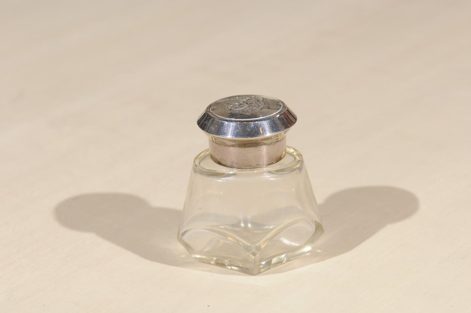 An English crystal toiletry bottle from Birmingham circa 1924, with silver lid. Born in the West Midlands region of England during the early years of the 20th century, this lovely toiletry bottle features a petite crystal body accented with a silver