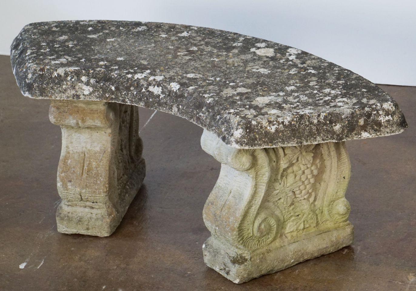 A fine English garden bench or seat of composition stone, featuring a curved top (39 1/2 inches length), set upon two plinth supports with a scroll and grape relief design.

Note: The depth of the curved seat is 15 inches - the overall depth from