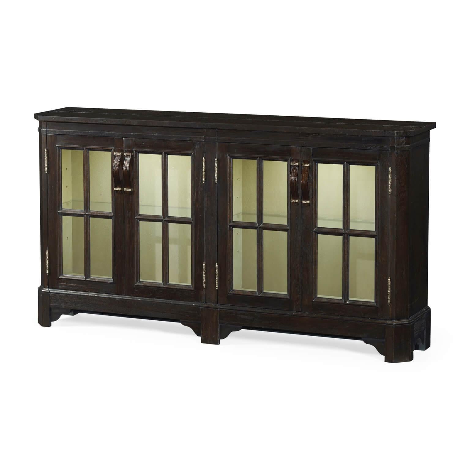 English dark ale country style planked low bookcase with internal lighting, four doors, and adjustable glass shelves. Intricate wooden strap handles with parquet brass details on the door fronts.

Dimensions: 66 7/8