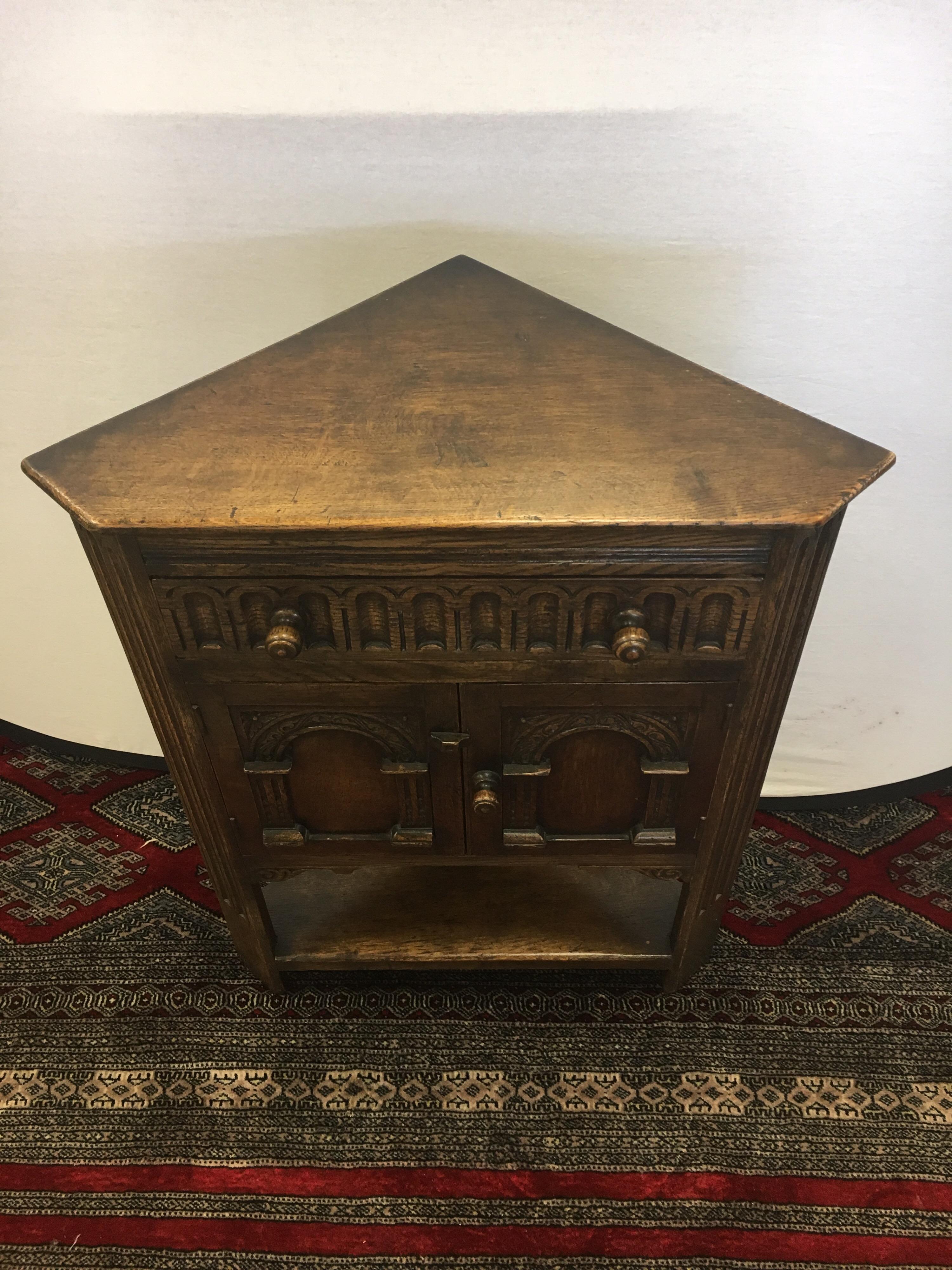 Old dark oak corner table cabinet from famed George Fleet & Co. Ltd. of Stoke on Trent in England and hallmarked on back. Features carved doors and detail. Has top drawer and double doors that open for storage. It’s small size can fit in any space.