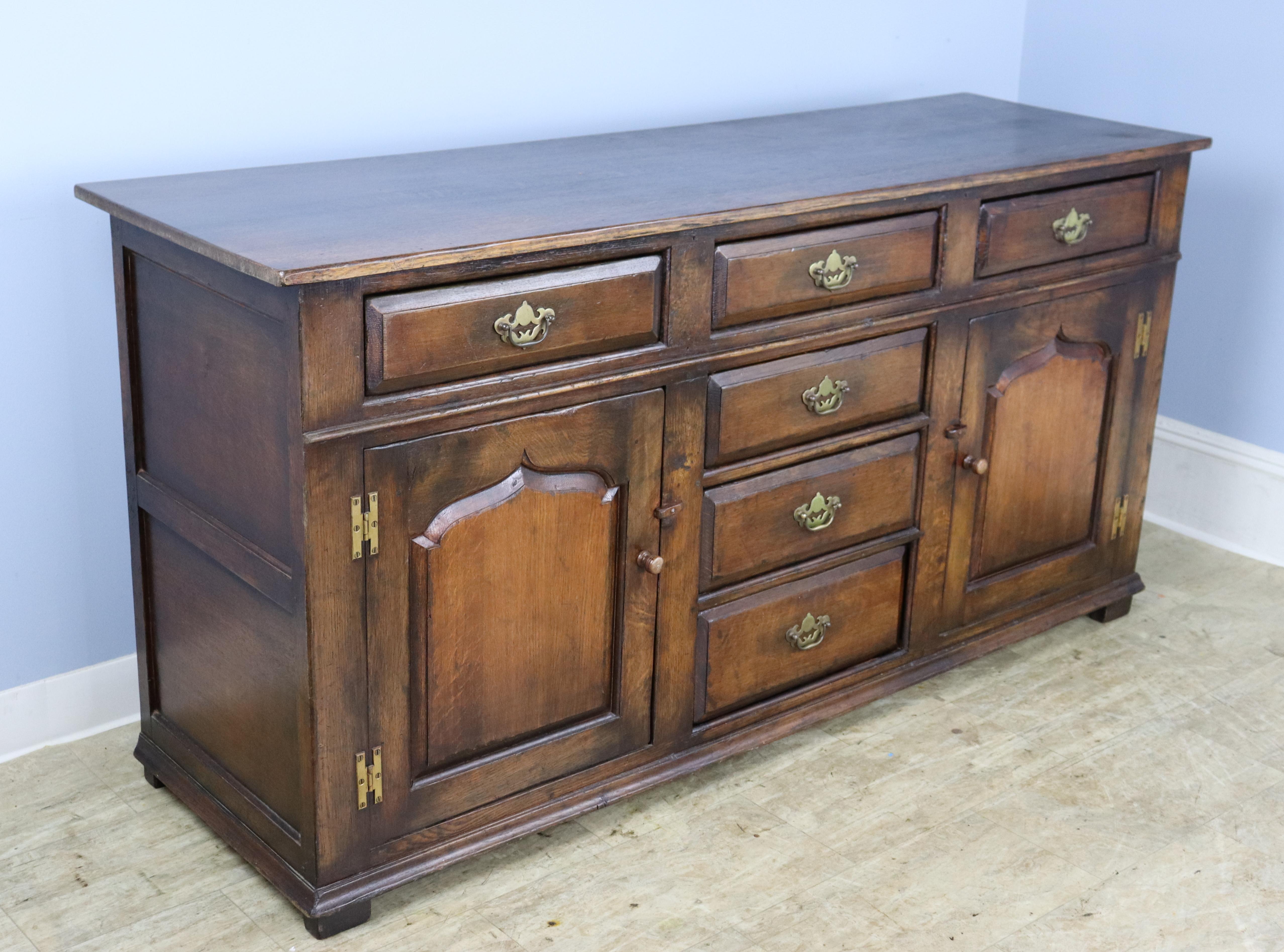 An elegant dark oak dresser base with lots of excellent storage. The six roomy drawers are clean and slide easily. The outset panels on the drawers and doors, as well as the top, have good oak grain and patina.
