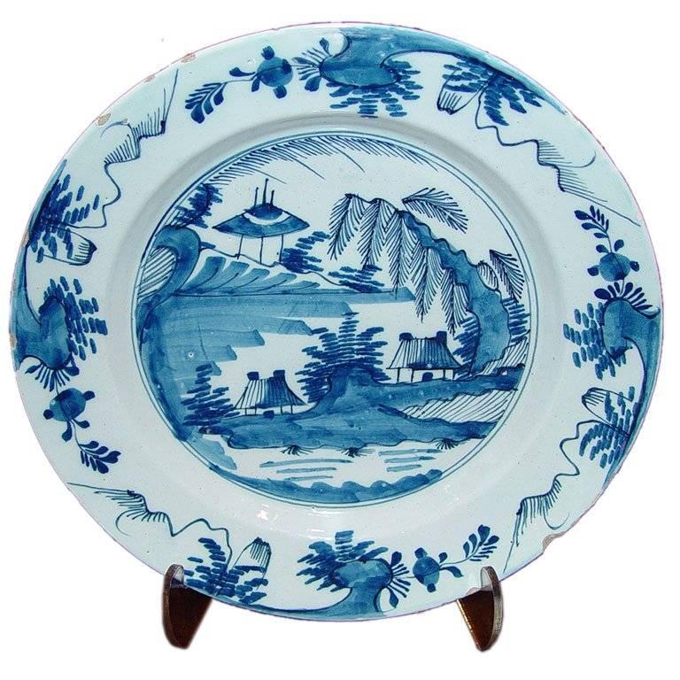 Good quality 18th C English blue and white Delft charger depicting cottages on a river.