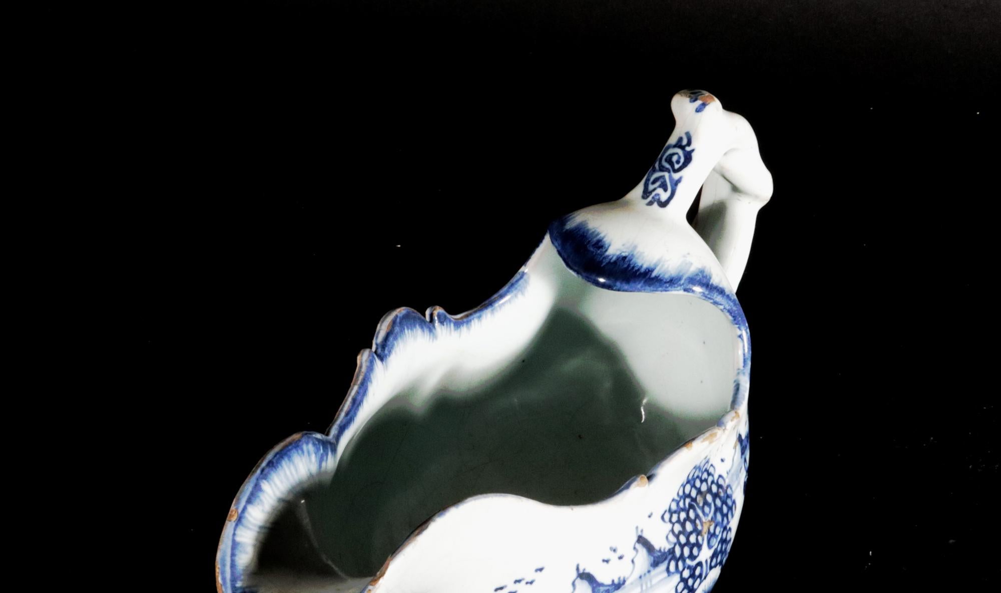 Barattolo per Sauce inglese in bianco e blu, 
Londra,
Circa 1790

La salsiera inglese in bianco e blu, con beccuccio lungo e ricurvo e manico a forma di granchio, è decorata con un disegno a cineserie di edifici e paesaggi e ha una forma rococò con