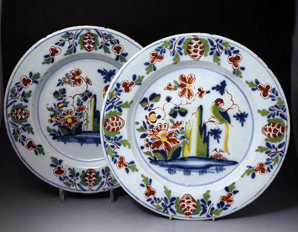 An excellent pair of English delftware chargers strongly decorated in polychrome with flowers and a parrot perched on a branch stemming from a rocky outcrop, mid-18th century. This pattern is seen mainly on plates, it is rare to locate a pair of