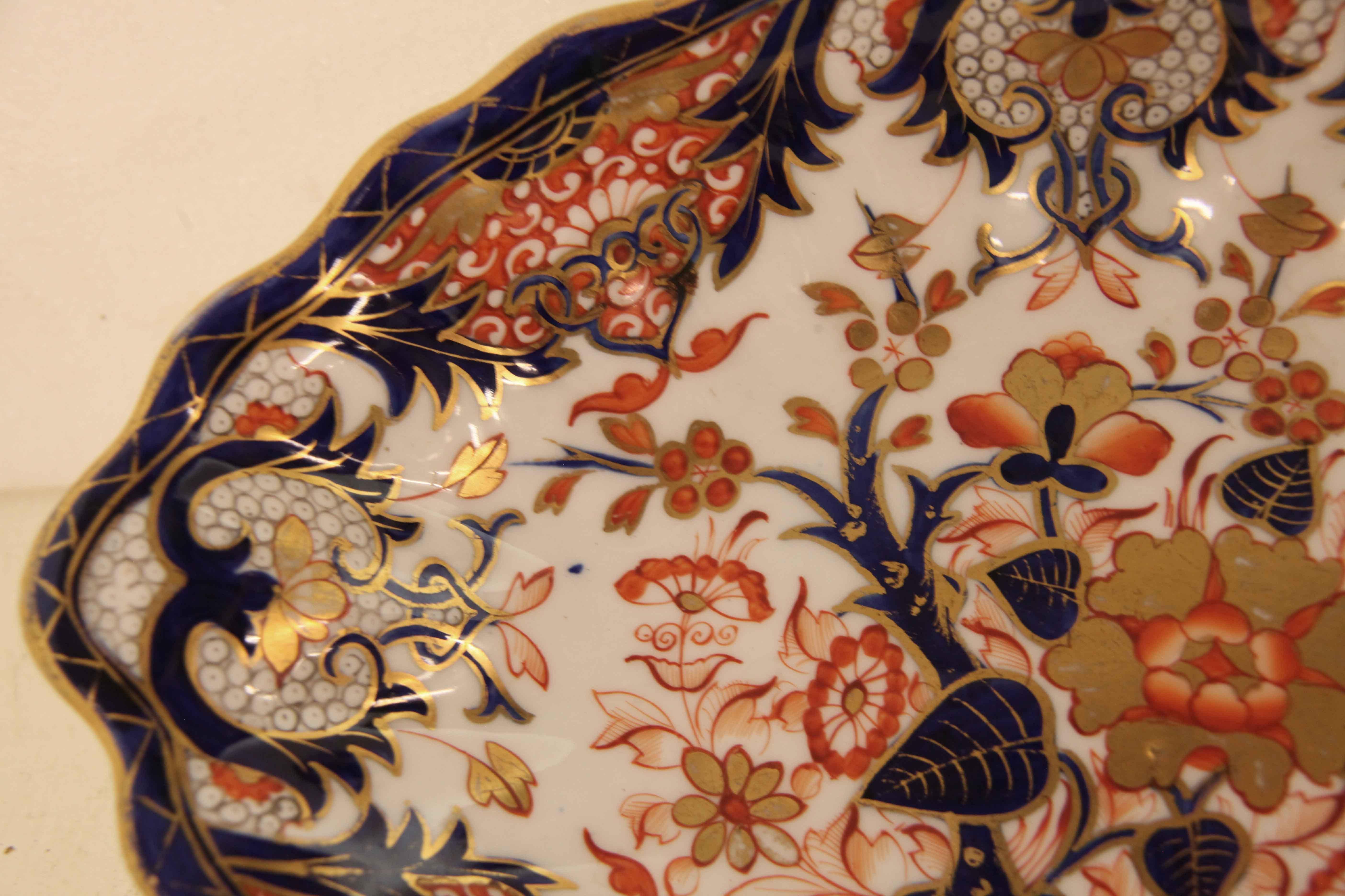 Ovale Schale English Derby,  der Rand und die Randeinfassung haben eine gewellte Form. Diese Schale zeigt eine Vielzahl von floralen und skurrilen Motiven in den typischen Derby-Farben oder tiefem Kobalt, Lachs und Orange auf weißem Grund.  Mit der