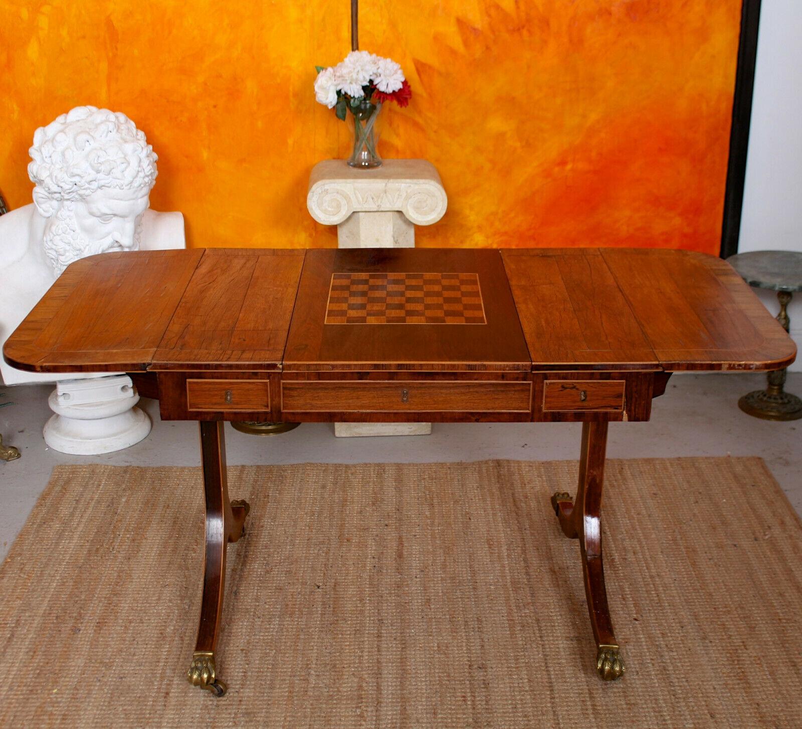 An impressive and rare drop-leaf walnut veneered writing desk.
The rectangular rosewood crossbanded top with drop leaves having central sliding board inlaid as drafts, chess and backgammon. Raised on standards with sabre legs having brass paw