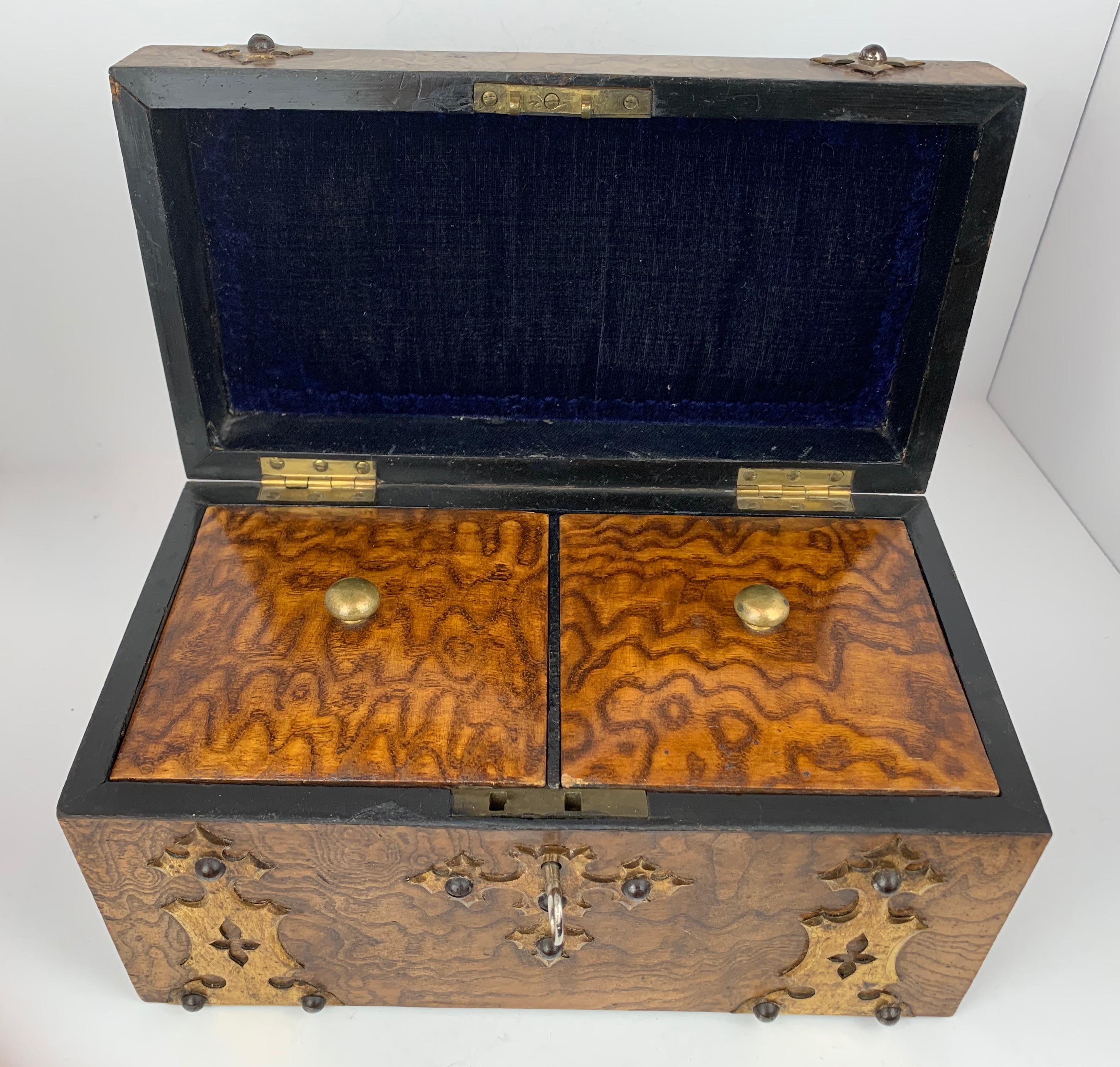 Antique English tea caddy made from Carpathian Elm with two compartments for two different teas. The exterior is embellished with brass trim and studs. The compartments are lined with marbleized paper.