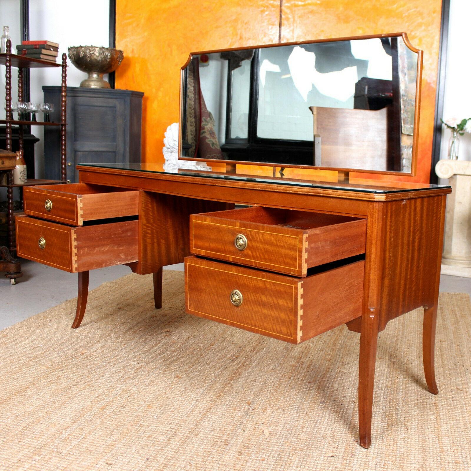 An impressive inlaid mahogany dressing table originally retailed by Maple & Co.

An adjustable mahogany framed mirror raised on supports. The inlaid top with canted corners and glass top. Fitted four drawers to the twin pedestals with inlaid