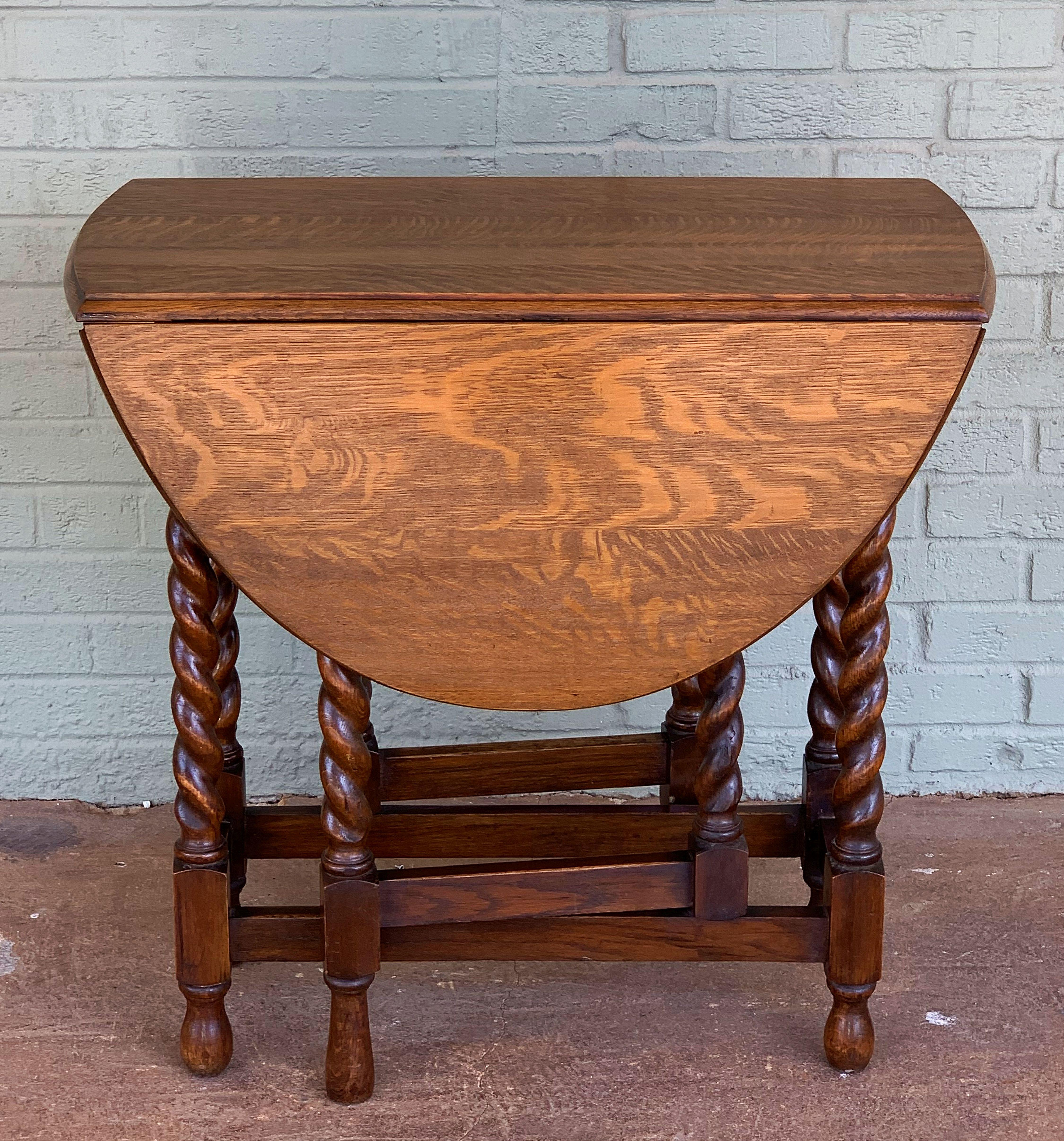 A Classic English drop-leaf gate-leg table of oak, featuring a moulded top with drop-down sides, over a stretcher of six barley-twist supports.
Opens to an oval top.

Measures: Height 28 3/4 inches
Width 30 inches
Depth (Closed) 15 3/4 inches