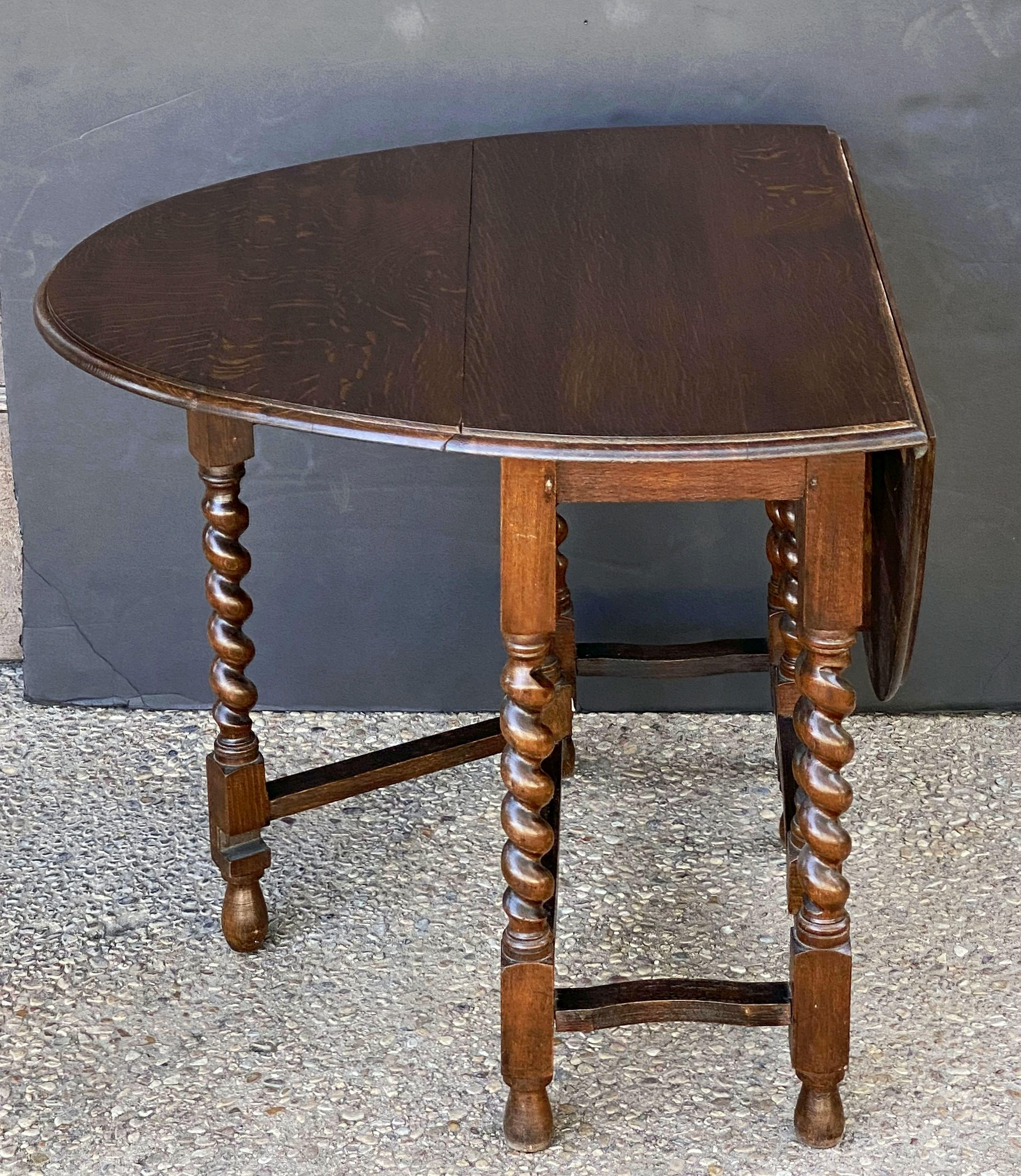 A Classic English drop-leaf gate-leg table of oak, featuring a moulded top with drop-down sides, over a stretcher of six barley-twist supports.
Opens to an oval top.

Measures: 

Height 28 inches
Width 34 3/4 inches
Depth (Closed) 16 1/4