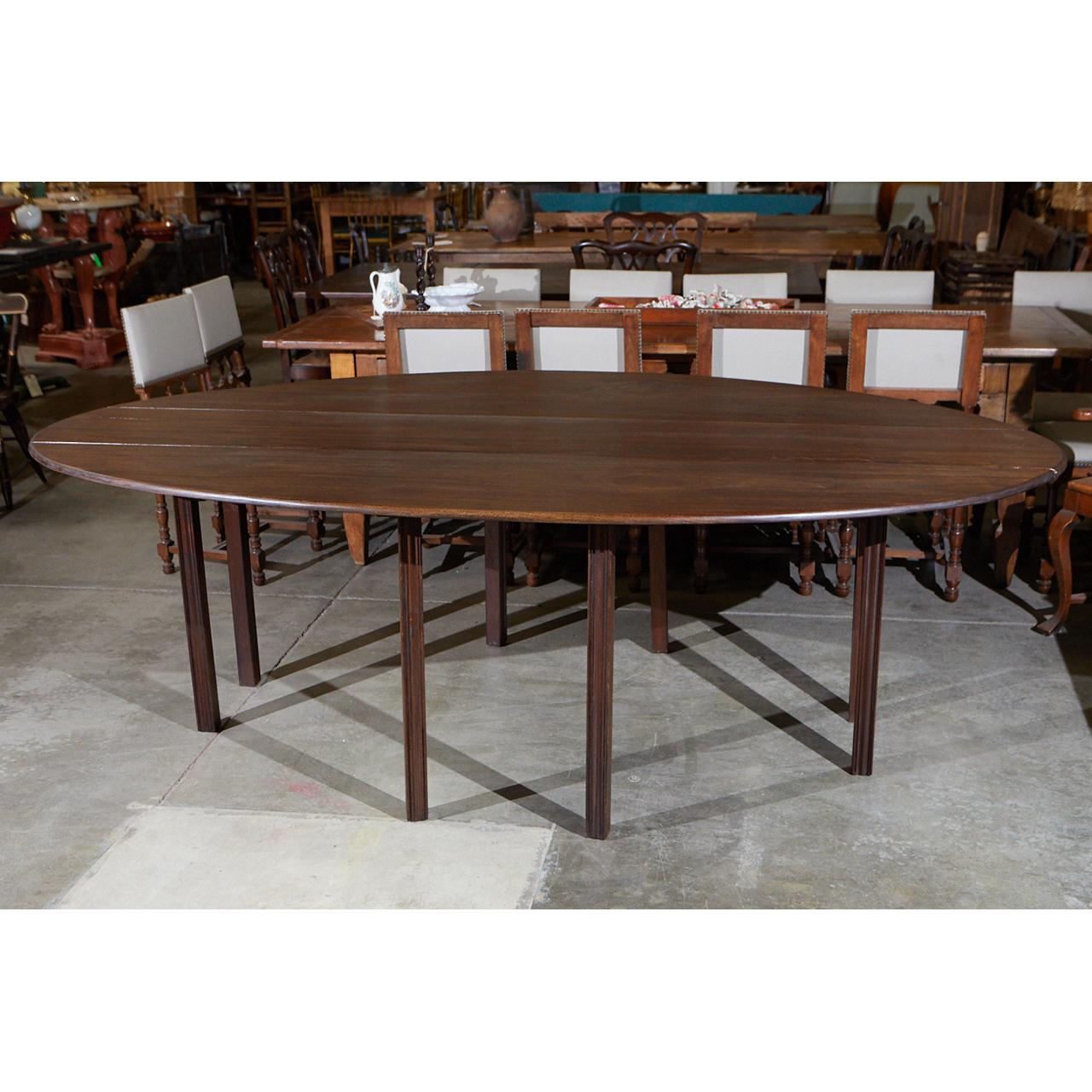 This large, oval drop leaf table was purchased in the Cotswolds in England and is from the 1960s. It is beautifully made with nicely beveled edges and eight reeded legs. The drop leaves gives it the versatility to suit a variety of orientations in