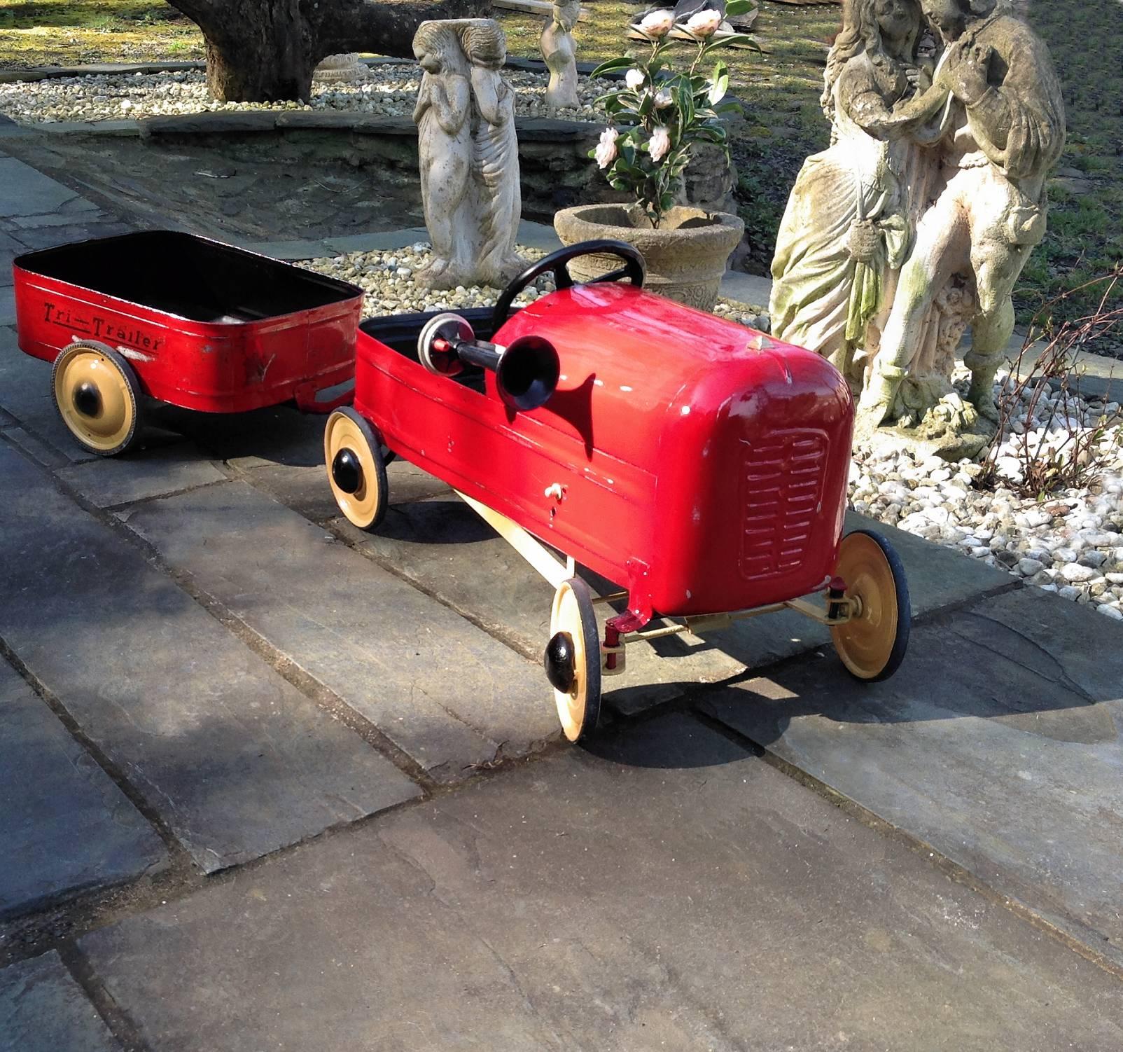 This is a wonderful opportunity to acquire British made 1950s pedal car and matching trailer. Professionally restored to enhance the patina and show off its Classic colors and contours. Embellished with a vintage air horn. The pedal car and trailer