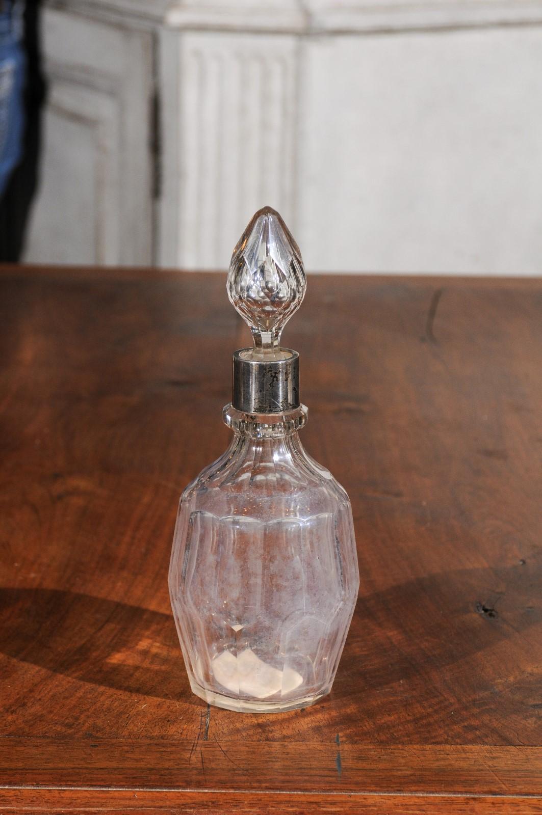 An English crystal and silver toiletry bottle from the early 19th century, with stopper. Born in England during the second decade of the 19th century, this toiletry bottle features a crystal faceted body, accented with a circular silver neck. Topped